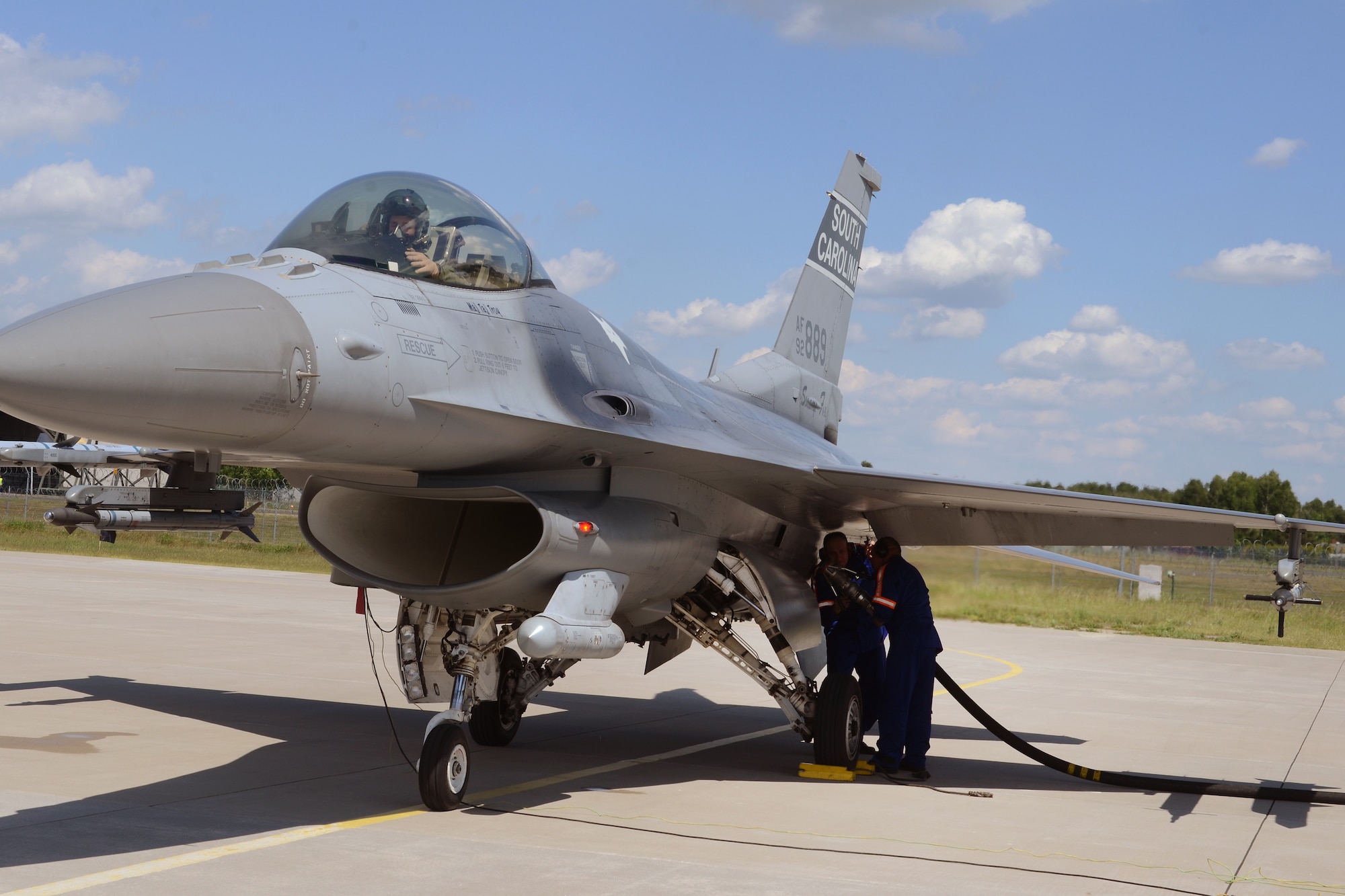 Polish air force Young Warrant Officer Adam Maksymowicz and Senior Sgt. Pawel Czapski, both from the 32nd Tactical Air Base at Łask Air Base, Poland, "hot-pit" refuel a South Carolina Air National Guard F-16 fighter jet, piloted by Capt. Mark "Dirty" Fattman, June 1, 2015. F-16 aircraft maintenance crews from the Polish 32nd Tactical Air Base and the South Carolina Air National Guard's 169th Fighter Wing teamed-up to conduct "hot-pit" refueling at Łask Air Base, Poland, June 1, 2015. The 32nd Tactical Air Base was recently certified to perform "hot-pit" refueling, which involves refueling a recently landed F-16 so that it can take off for another mission without stopping its engine. Three units worked together to learn "hot-pitting" techniques from each other as well as offering opportunities for Polish Airmen to learn from the more seasoned 169th Fighter Wing and 52d Fighter Wing maintainers. U.S. Air Force Airmen from Spangdahlem Air Base, Germany and the South Carolina Air National Guard’s 169th Fighter Wing from McEntire Joint National Guard Base, are deployed to Łask Air Base in support of Operation Atlantic Resolve, during the month of June. These training missions, called Aviation Detachment Rotations, pair U.S. fighter pilots and maintenance crews with their Polish Air Force counterparts at Łask Air Base, during Operation Atlantic Resolve. This bilateral training, hosted by permanently assigned USAF service members assigned to Poland, has taken place since 2012. Through strengthened relationships and engagements with our allies, the U.S. and NATO demonstrate their shared commitment to a peaceful, stable and secure Europe. (South Carolina Air National Guard photo by Senior Master Sgt. Edward Snyder / RELEASED)
