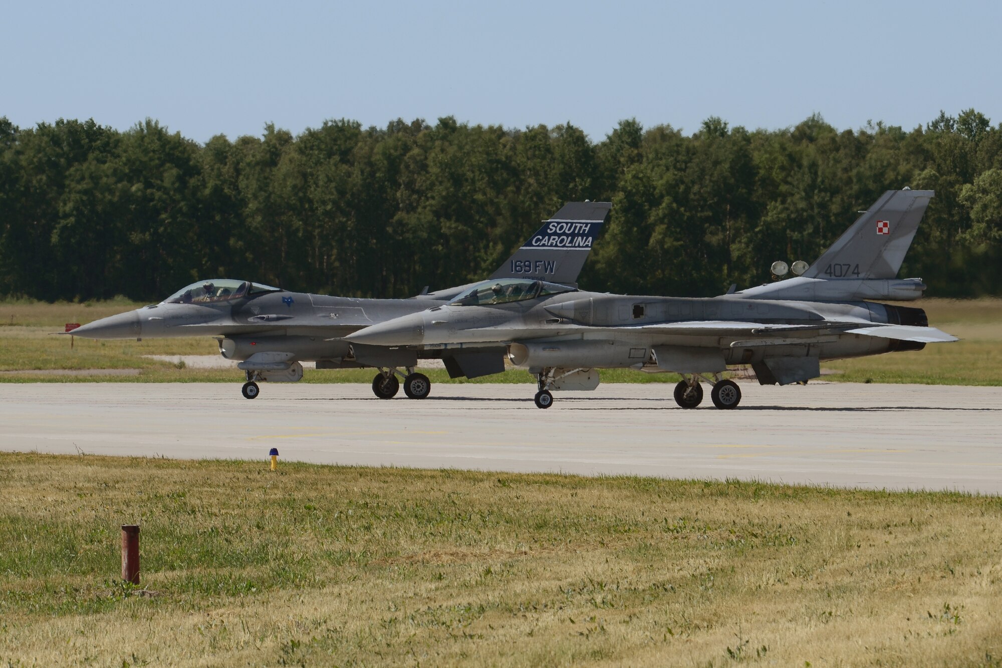 F-16 fighter jets from Poland's 32nd Tactical Air Base and the South Carolina Air National Guard prepare to taxi for takeoff at Łask Air Base, Poland in support of Operation Atlantic Resolve, June 5, 2015. U.S. Air Force Airmen from Spangdahlem Air Base, Germany, and the South Carolina Air National Guard’s 169th Fighter Wing from McEntire Joint National Guard Base, are deployed to Łask Air Base in support of Operation Atlantic Resolve, during the month of June. These training missions, called aviation detachment rotations, pair U.S. fighter pilots and maintenance crews with their Polish air force counterparts at Łask Air Base, during Operation Atlantic Resolve. This rotation, AvDet 15-3, is the first to combine guard/reserve and active-duty units in Poland to offer more diverse opportunities to share best practices and build professional relationships with the Polish air force. This bilateral training, hosted by permanently assigned USAF service members assigned to Poland, has taken place since 2012. Through strengthened relationships and engagements with our allies, the U.S. and NATO demonstrate their shared commitment to a peaceful, stable and secure Europe. (South Carolina Air National Guard photo by Senior Master Sgt. Edward Snyder / RELEASED)