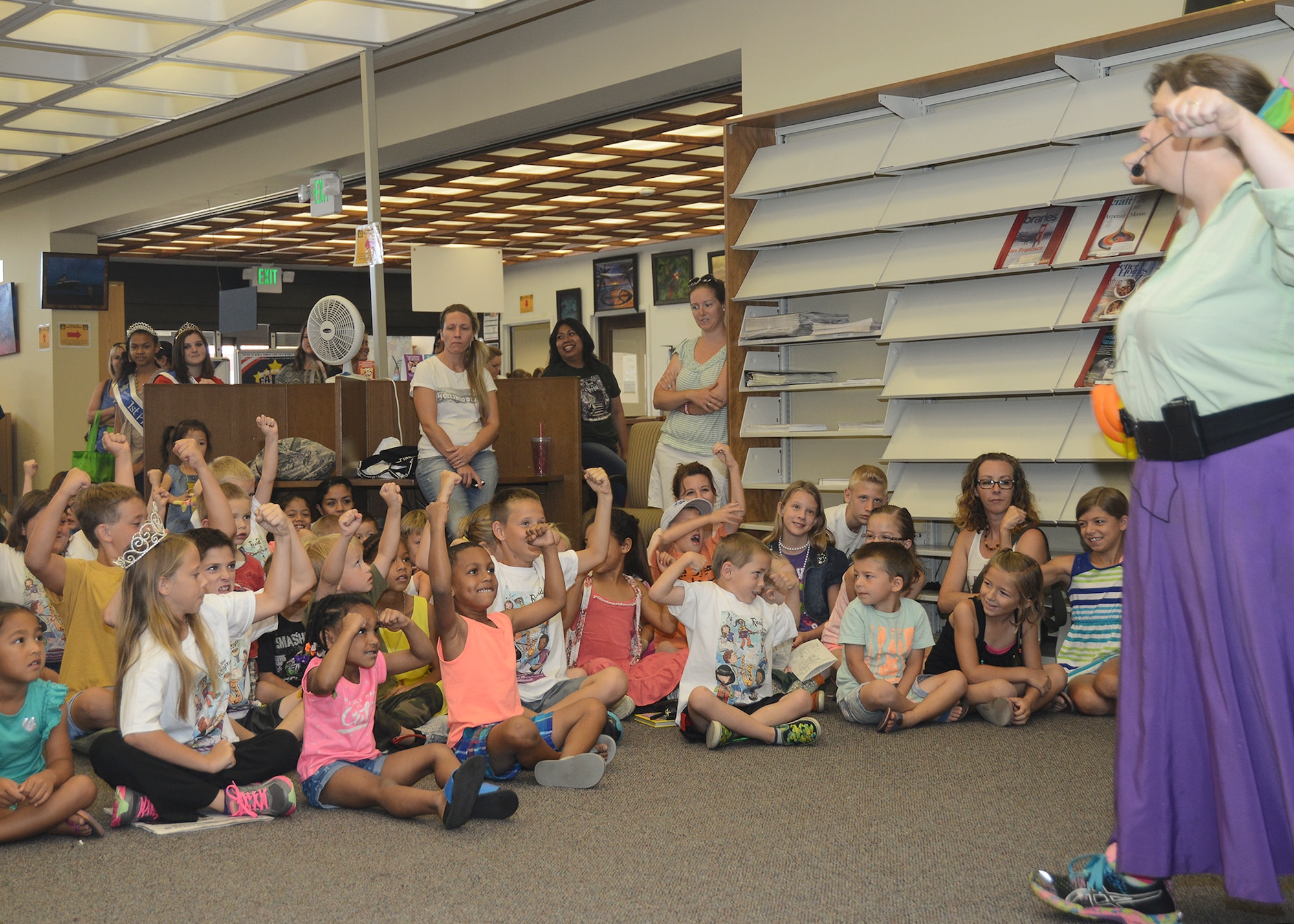 An audience of children show their strength as Annie Banannie searches for a superhero to save the day as the local storyteller performs for the base library’s 2015 Summer Reading Program event. The interactive story was performed by a highly passionate cast of actors drawn from the audience. In this case, the crowd channels their inner hero strength as Annie searches for the protagonist to her story. (U.S. Air Force photo by Patric Lovato)