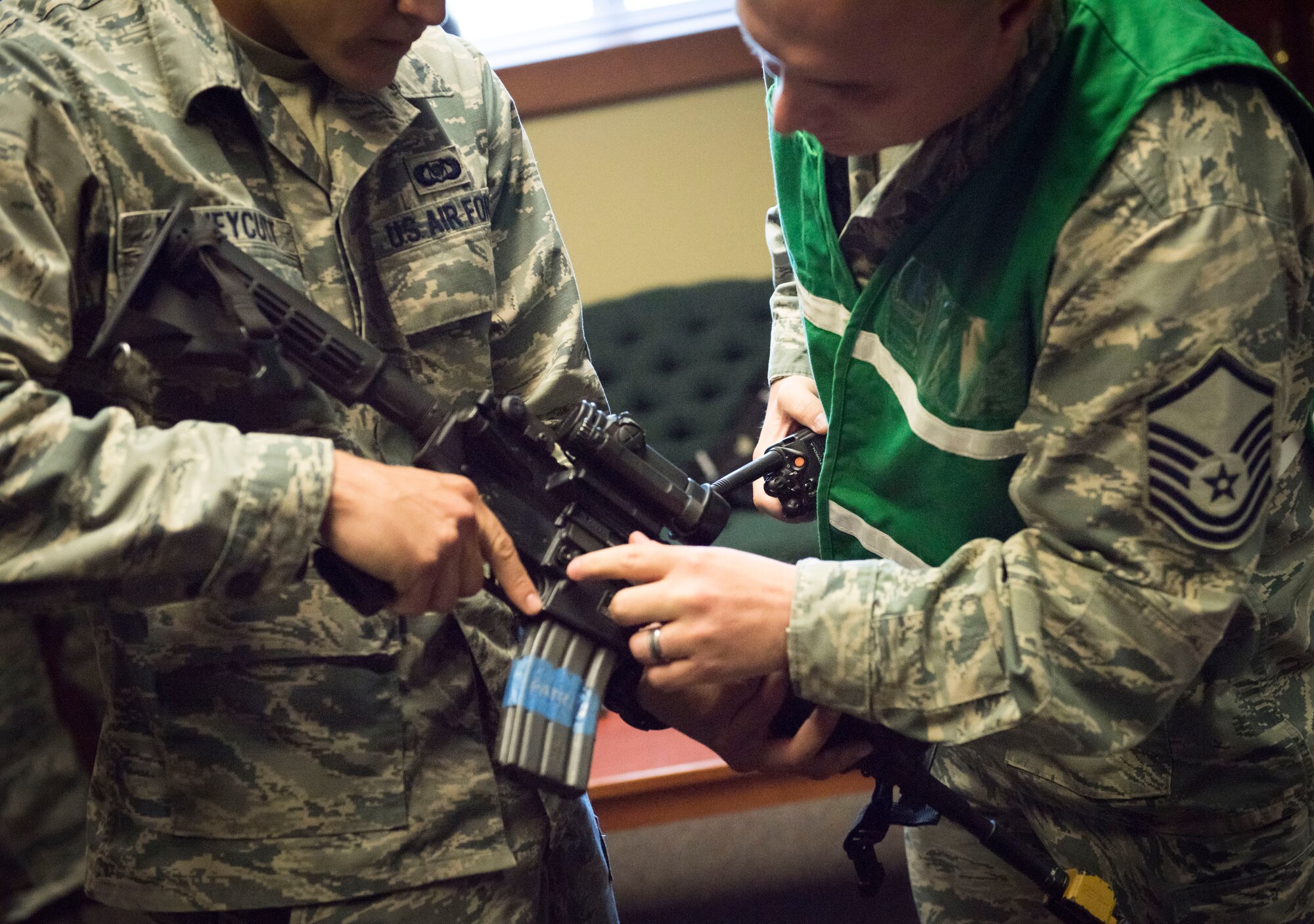 Master Sgt. Otis Chatham, 366th Security Forces Squadron NCO in charge of standardizations and evaluations, shows Senior Airman Kyle Honeycutt, role player pretending to be an active shooter, how to handle the weapon before the exercise June 18, 2015, at Mountain Home Air Force Base, Idaho. Chatham escorted Honeycutt around the 366th Operations Suppport Squadron building during the exercise. (U.S. Air Force photo by Airman 1st Class Jeremy L. Mosier/RELEASED)