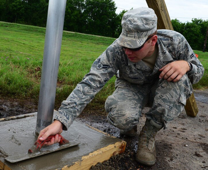 Airman 1st Class Zachary Aronin, 2nd Civil Engineer Squadron paving and equipment technician, smooths the concrete on the base of a new memorial sign on Barksdale Air Force Base, La., June 18, 2015. The small sign represents a big piece of history and has information about the 1951 Bossier Base on it. (U.S. Air Force photo/Airman 1st Class Luke Hill)