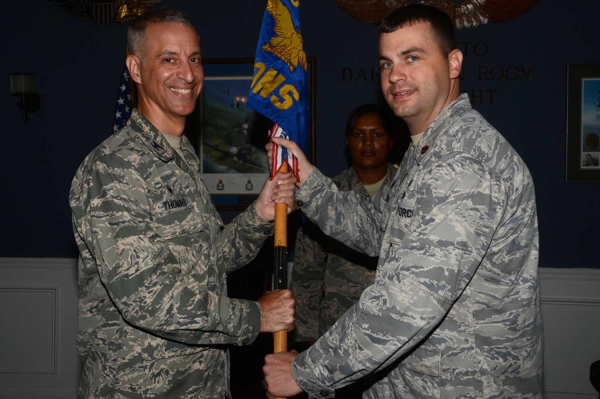 U.S. Air Force Maj. John Kendall, 20th Contracting Squadron commander (right), passes the squadron guidon as he relinquishes command of the unit to Col. John Thomas, 20th Mission Support Group commander, during an Assumption of Leadership ceremony at Shaw Air Force Base, S.C., June 16, 2015. Kendall was the 20th CONS commander for three years. (U.S. Air Force photo by Senior Airman Jonathan Bass/Released)