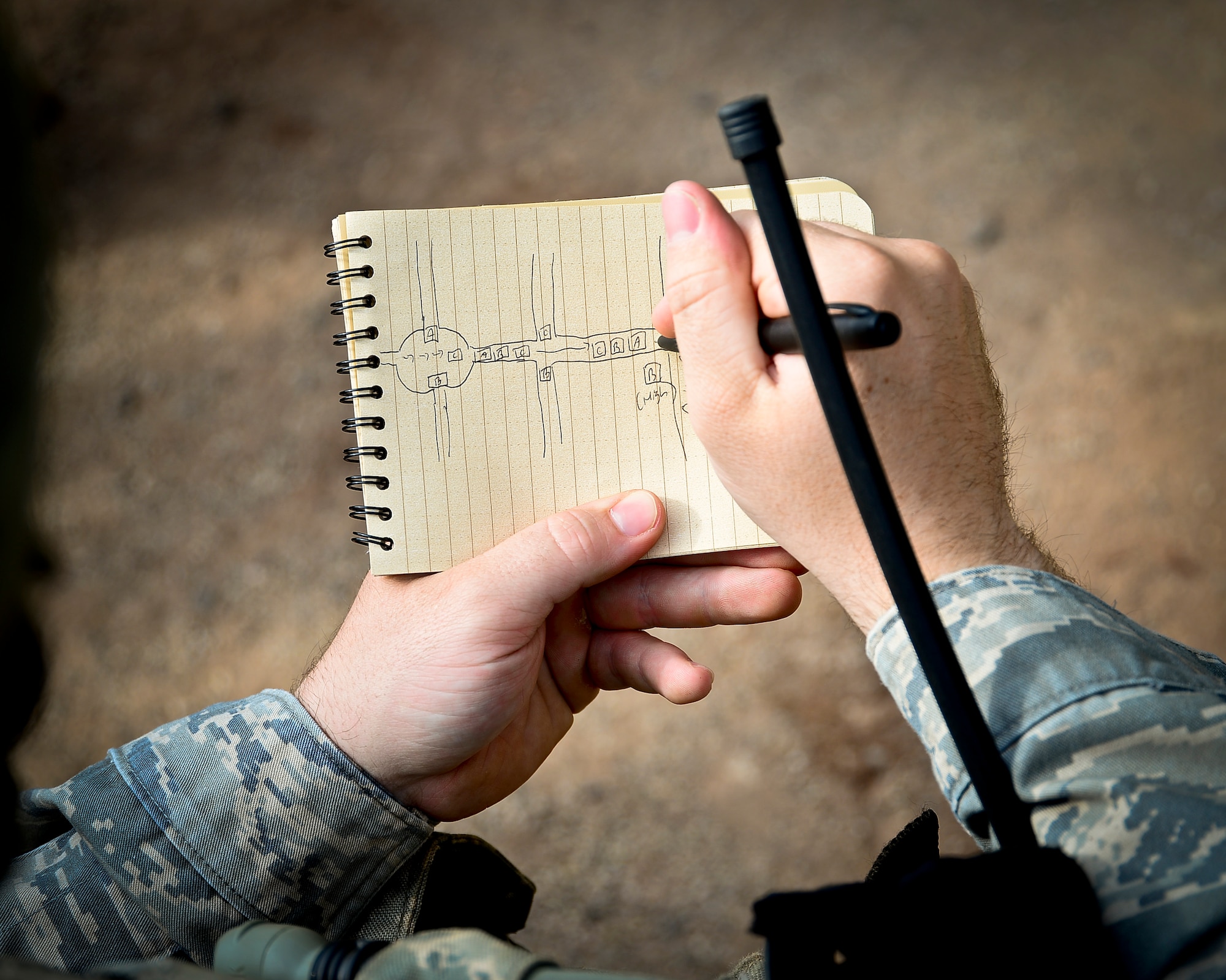 A student sketches from the sand table for a mission rehearsal during the base security operations course on Baumholder, Germany, June 15, 2015.  Sand tables are used to conduct rehearsals prior to missions.  (U.S. Air Force Photo/Tech. Sgt. Daylena S. Ricks)