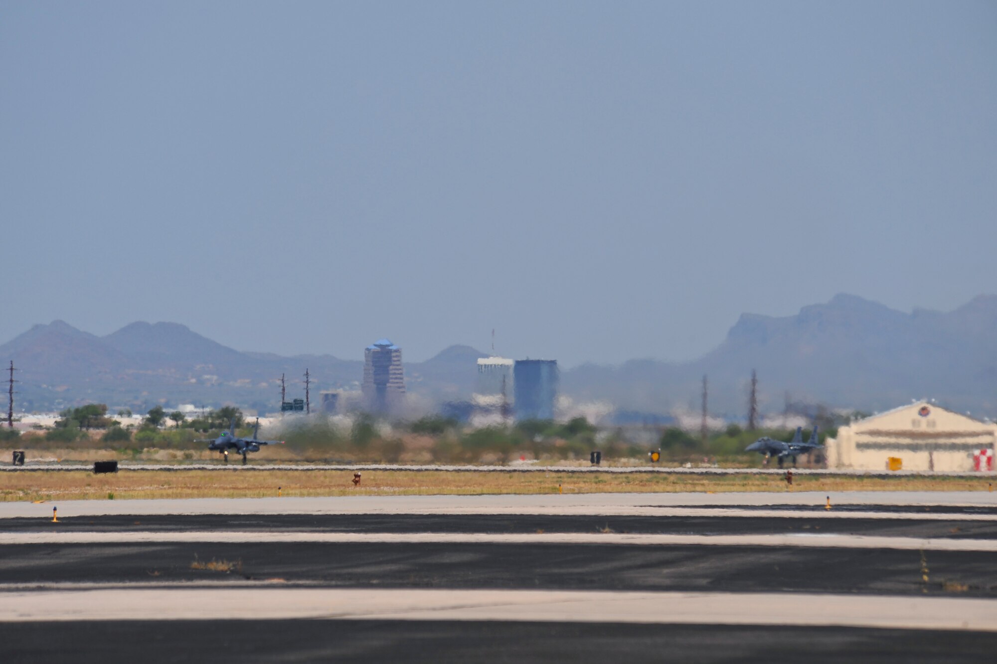 An F-15E Strike Eagle from the 334th Fighter Squadron, Seymour Johnson Air Force Base, takes off from the runway as another F-15E stands by for takeoff at Davis-Monthan AFB, Ariz., June 22, 2015. Fourteen Strike Eagles will be completing their Surface Attack Tactics phase training in military training areas from June 12-27. (U.S. Air Force photo by Airman 1st Class Chris Massey/Released)