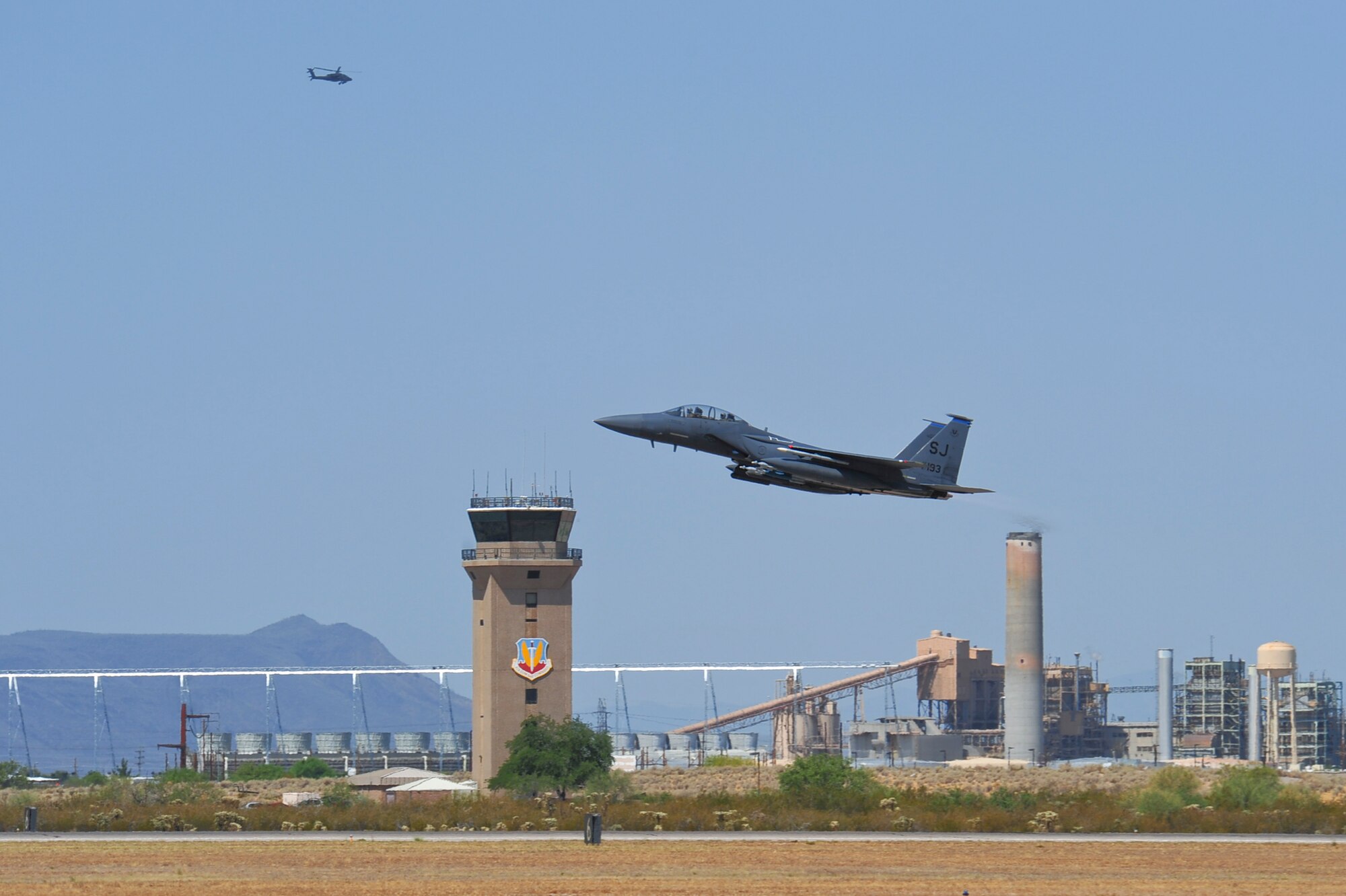 An F-15E Strike Eagle from the 334th Fighter Squadron, Seymour Johnson Air Force Base, N.C., takes off from the runway at Davis-Monthan AFB, Ariz., while a helicopter flies by June 22, 2015. Fourteen F-15E Strike Eagles from Seymour Johnson AFB trained with F-35A Lightning IIs, F-16 Fighting Falcons and A-10 Thunderbolt IIs throughout southern Arizona’s military operating areas.  (U.S. Air Force photo by Airman 1st Class Chris Massey/Released)