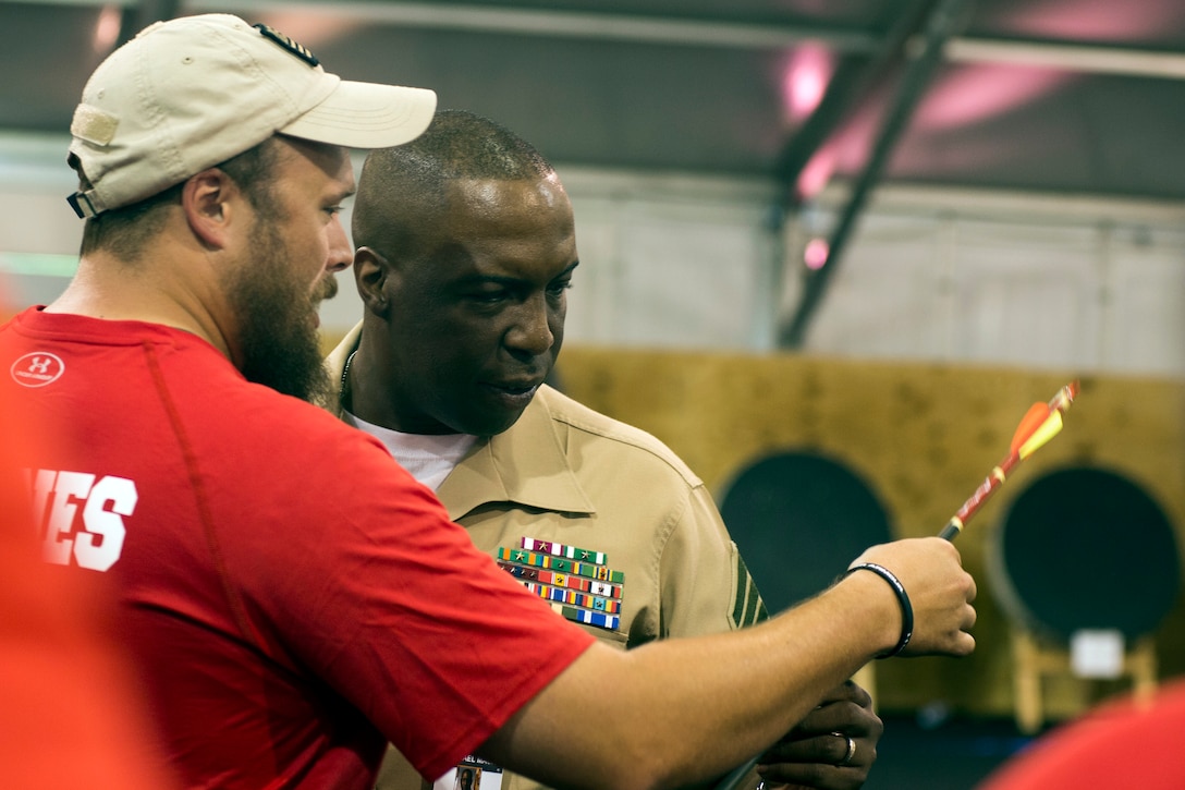 Retired U.S. Marine Corps Sgt. Clayton McDaniel hands Sgt. Maj. Michael Mack his silver medal-winning arrow at the 2015 Department of Defense Warrior Games archery competition on Marine Corps Base Quantico, Va., June 22, 2015. 