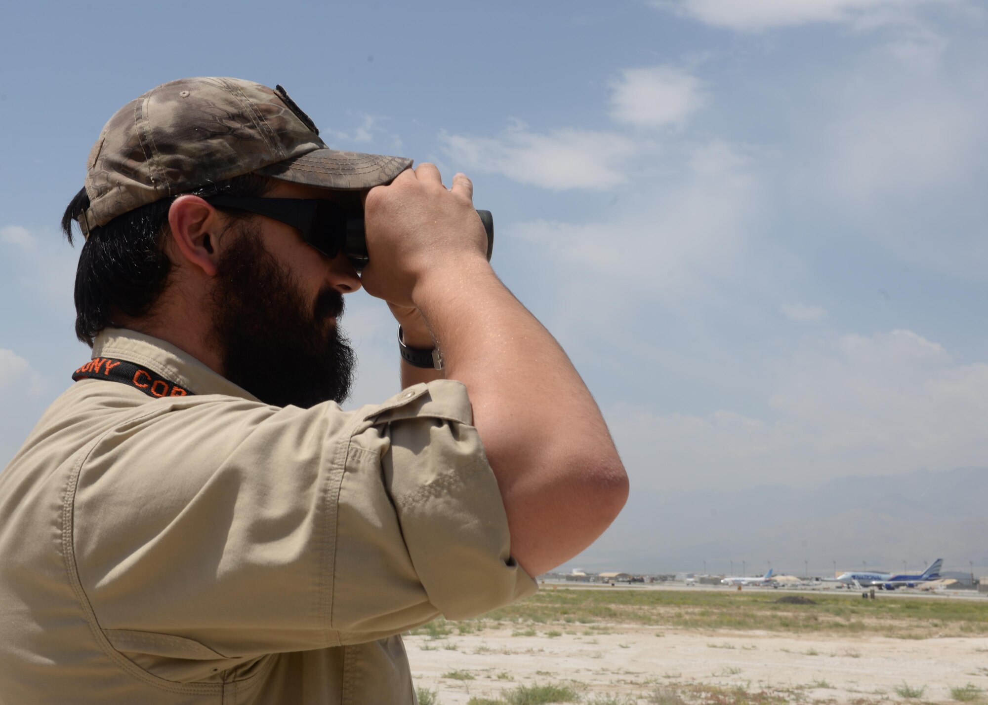 Matthew Gage, 455th Expeditionary Safety Office wildlife biologist, looks for birds and wild life on the flight line through his binoculars June 22, 2015, at Bagram Airfield, Afghanistan.  Gage is responsible for safely removing animals and birds that cause a risk to flight line and aircraft operations. (U.S. Air Force photo by Senior Airman Cierra Presentado/Released)