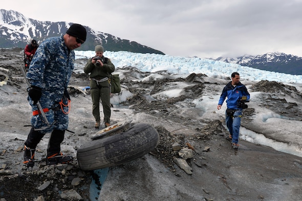 Navy Lt. Cmdr. Paul Cocker (left), the Alaskan Command deputy chief of future operations and Operation Colony Glacier project officer, shows local media some of the aircraft debris from the 1952 C-124 Globemaster II accident, June 10, 2015. Each summer since 2012, ALCOM has supported Operation Colony Glacier by removing aircraft debris and assisting in the recovery of human remains to ensure closure for families who have lost loved ones. (U.S. Air Force photo/Tech. Sgt. John Gordinier) 