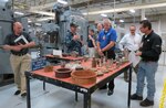 A group of executives from the heavy equipment giant, Caterpillar Inc. tour the production floor of Southeast Regional Maintenance Center during a familiarization tour to see how the Navy performs routine maintenance.