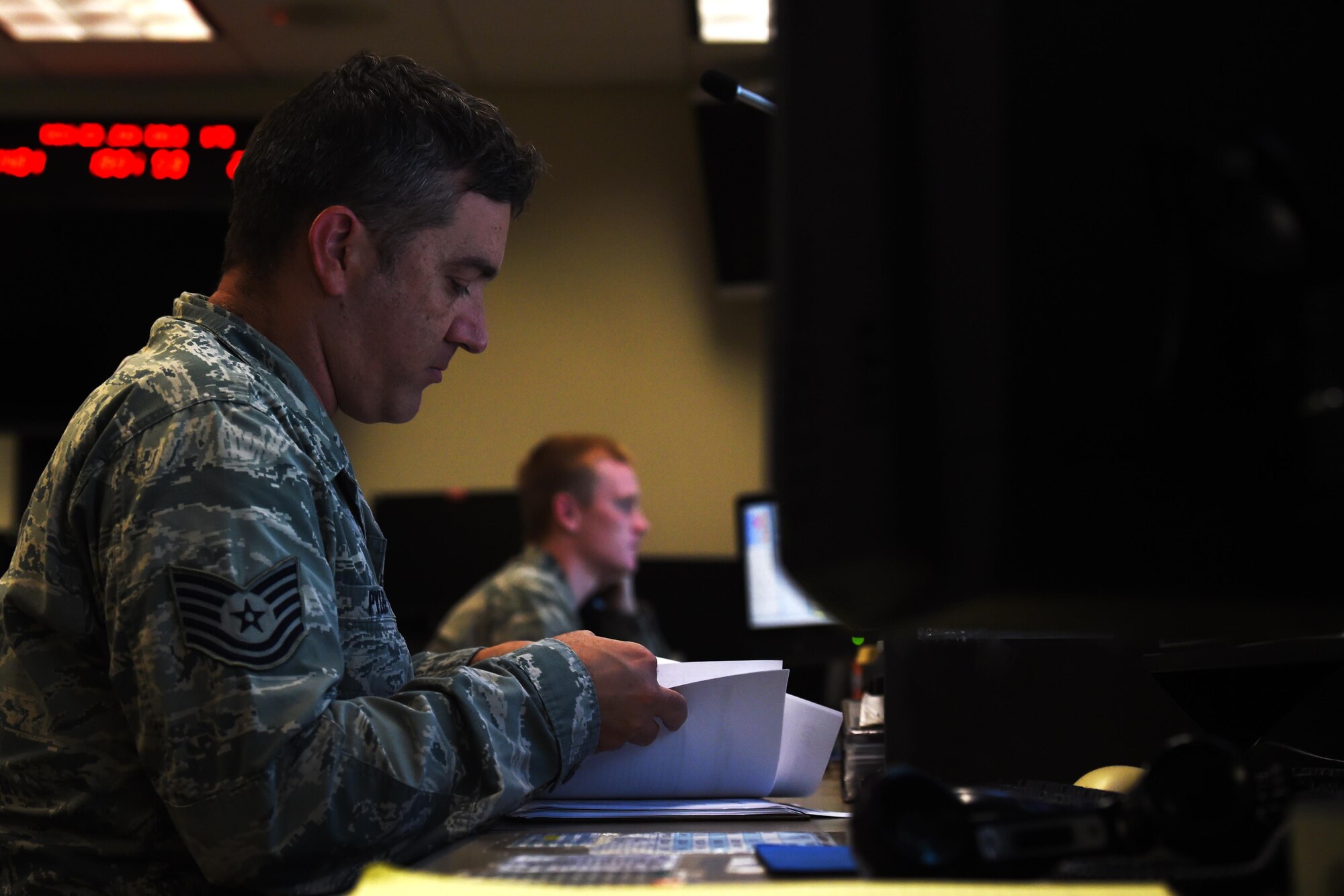 Tech. Sgt. Robert Pyles, 1st Special Operations Air Operations Squadron Command Post senior controller, flips through a message log book, June 22, 2015, at Hurlburt Field, Fla. Approximately 18 Command Post controllers work alternating shifts 24/7 to ensure base operations run smoothly. (U.S. Air Force photo by Airman 1st Class Ryan Conroy/Released)