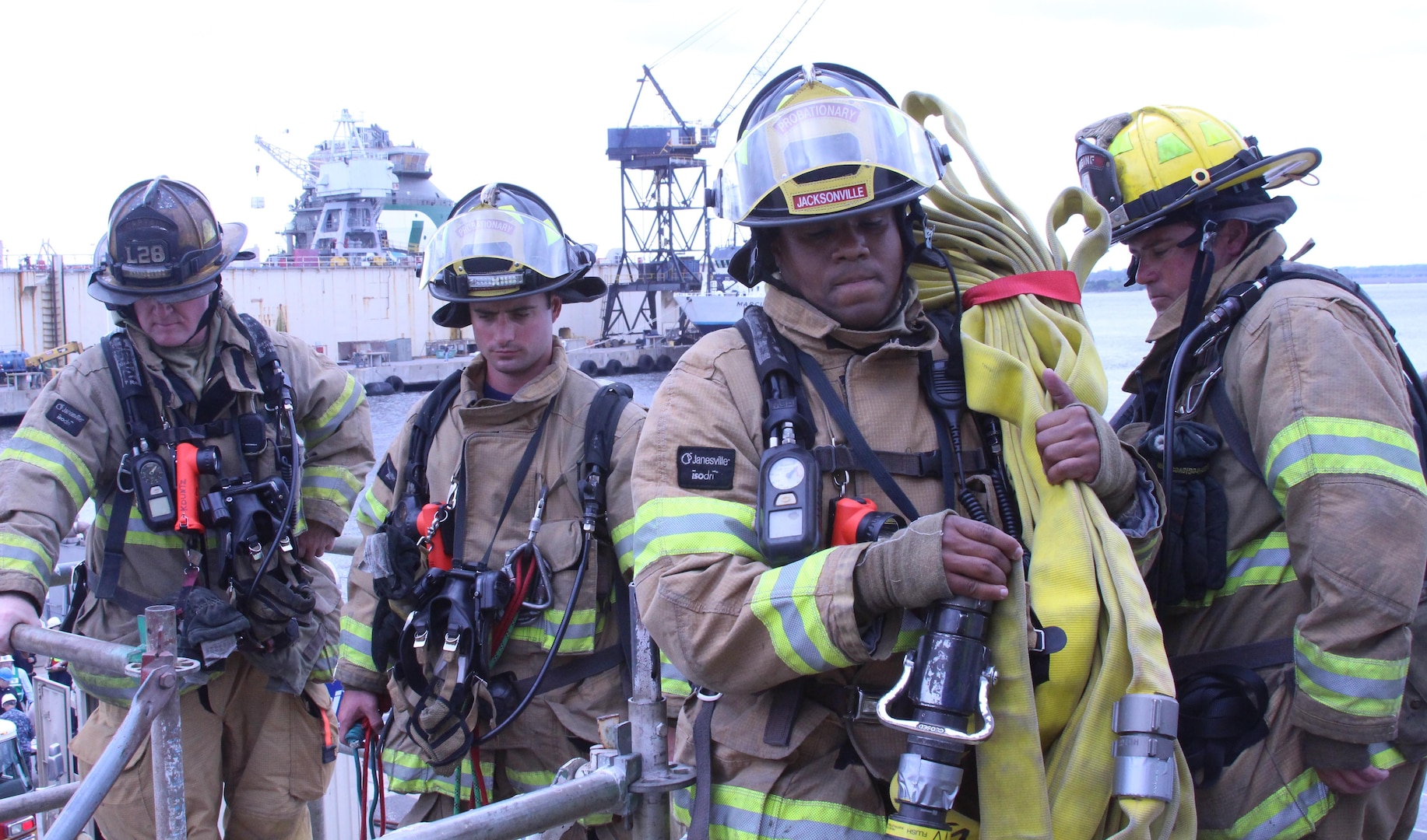 Members of JFRD haul equipment on board USS Tornado during a fire drill at the BAE Systems shipyard.  The local fire department was called in to augment the ship's crew and BAE first responders as a test of their ability to work together in a challenging shipyard environment.