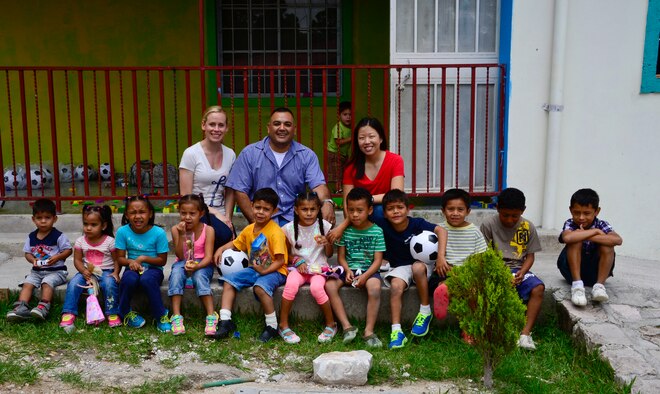 Staff Sgt. Katie Adams, Master Sgt. Roberto Vasquez and Capt. Sarah Hartenstein, all members of 12th Air Force (Air Forces Southern), take a group photo with the children at Casa de Corderitos orphanage outside the city of Tegucigalpa, Honduras, June 18, 2015. The 12th Air Force (AFSOUTH) members spent some of their downtime during a three-day assessment visit to Honduras air bases to volunteer with the local community and to deliver toys and candy that were donated by businesses in Tucson, Ariz. (U.S. Air Force photo/Tech. Sgt. Heather R. Redman)