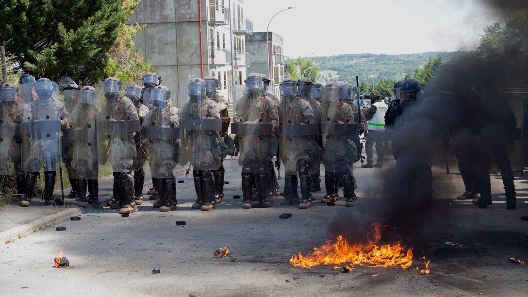 U.S. Marines with Special-Purpose Marine Air-Ground Task Force Crisis Response-Africa and members of Escadron de Gendarmerie Mobile, a law enforcement organization with a military status, known as the Gendarmerie, form a shield wall against rioters at the National Gendarmerie Training Center in St. Astier, France, June 19, 2015. The Marines trained to operate through dense smoke and riot-control gas while maintaining tightly organized formations.
