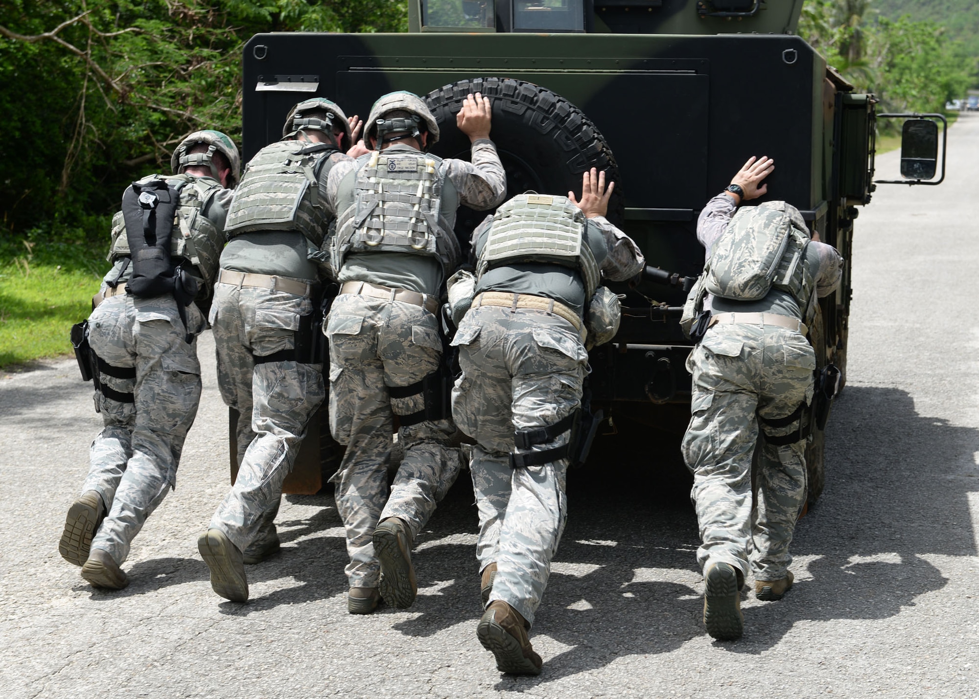 Airmen from the 36th Security Forces Squadron push a Humvee down a hill during the Defender Challenge June 22, 2015, at Andersen Air Force Base, Guam. Airmen tested their physical and mental strength through various obstacles and challenges during the competition, ending with a live-fire shooting course.  (U.S. Air Force photo by Airman 1st Class Joshua Smoot/Released)