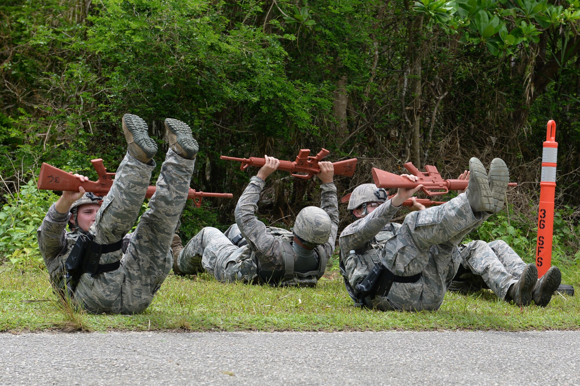 Airmen from the 36th Security Forces Squadron perform knee-ups while holding a training weapon during the Defender Challenge June 22, 2015, at Andersen Air Force Base, Guam. Airmen tested their physical and mental strength through various obstacles and challenges during the competition, ending with a live-fire shooting course. (U.S. Air Force photo by Airman 1st Class Joshua Smoot/Released)