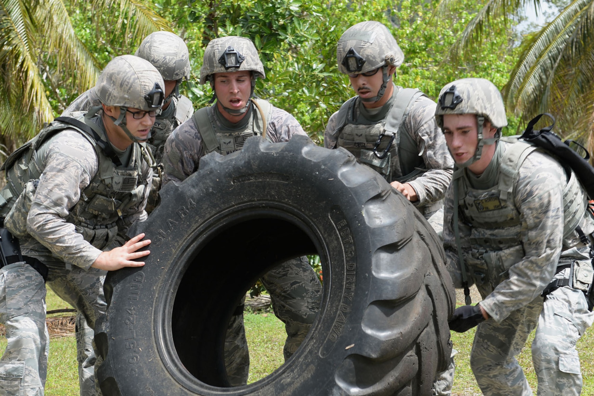 Airmen from the 36th Security Forces Squadron flip a tire during the Defender Challenge June 22, 2015, at Andersen Air Force Base, Guam. Airmen tested their physical and mental strength through various obstacles and challenges during the competition, ending with a live-fire shooting course. (U.S. Air Force photo by Airman 1st Class Joshua Smoot/Released)