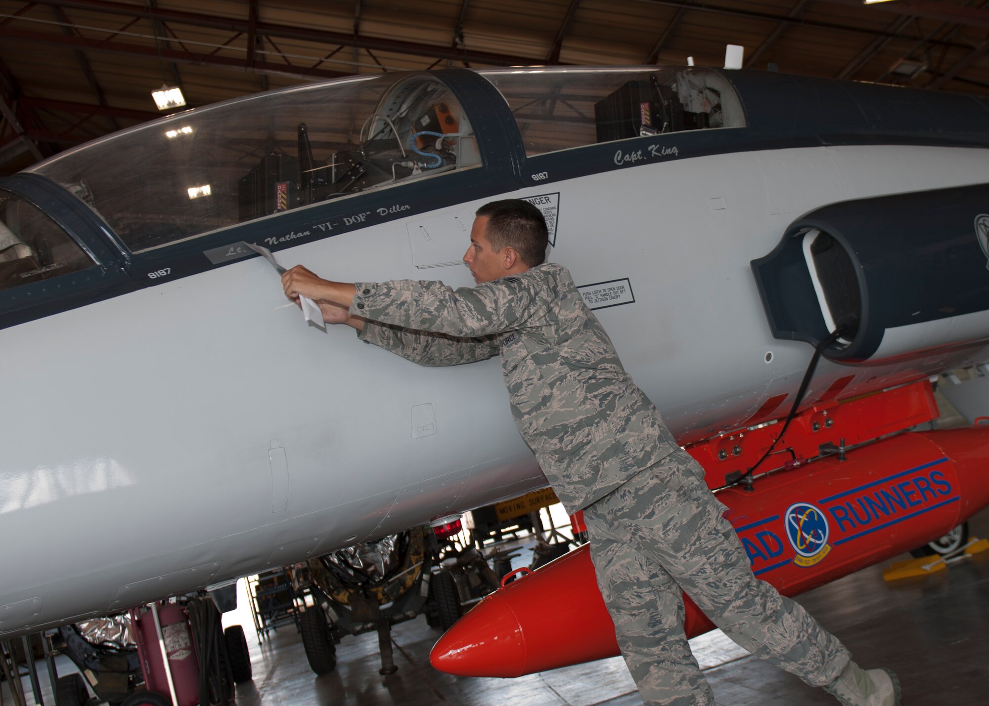 Tape is removed from a T-38C, revealing the name of the 586th Flight Test Squadrons incoming commander, Lt. Col. Nathan Diller, at Holloman Air Force Base, N.M., June 24, 2015. Diller assumed command from Lt. Col. Steven Ross and will use his 15 years of experience to continue the 586th FLTS mission of providing deployable operational support for test aircraft staging out of Holloman. (U.S. Air Force photo by Staff Sgt. Joe Laws / Released)