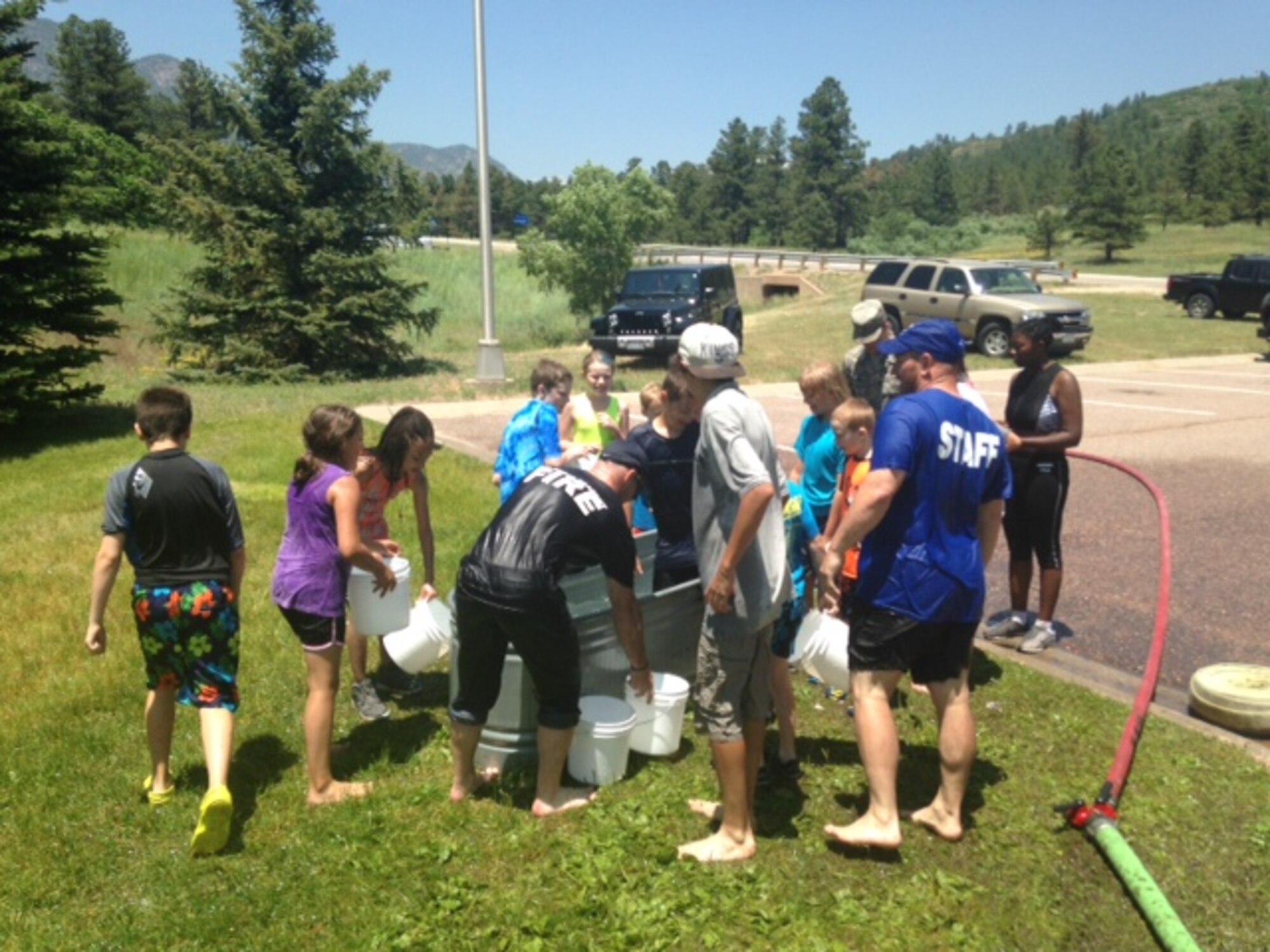 Children compete in the Bucket Brigade at the Fire Safety Camp at Fire Station 1 at the U.S. Air Force Academy June 23, 2015. Brigade competitors work in teams to fill a bin with water. The first team to fill a bin wins. The camp is an annual event hosted by the 10th Civil Engineer Squadron Fire Department to educate children about fire prevention and safety. (U.S. Air Force photo/Senior Airman Veronica Ward)