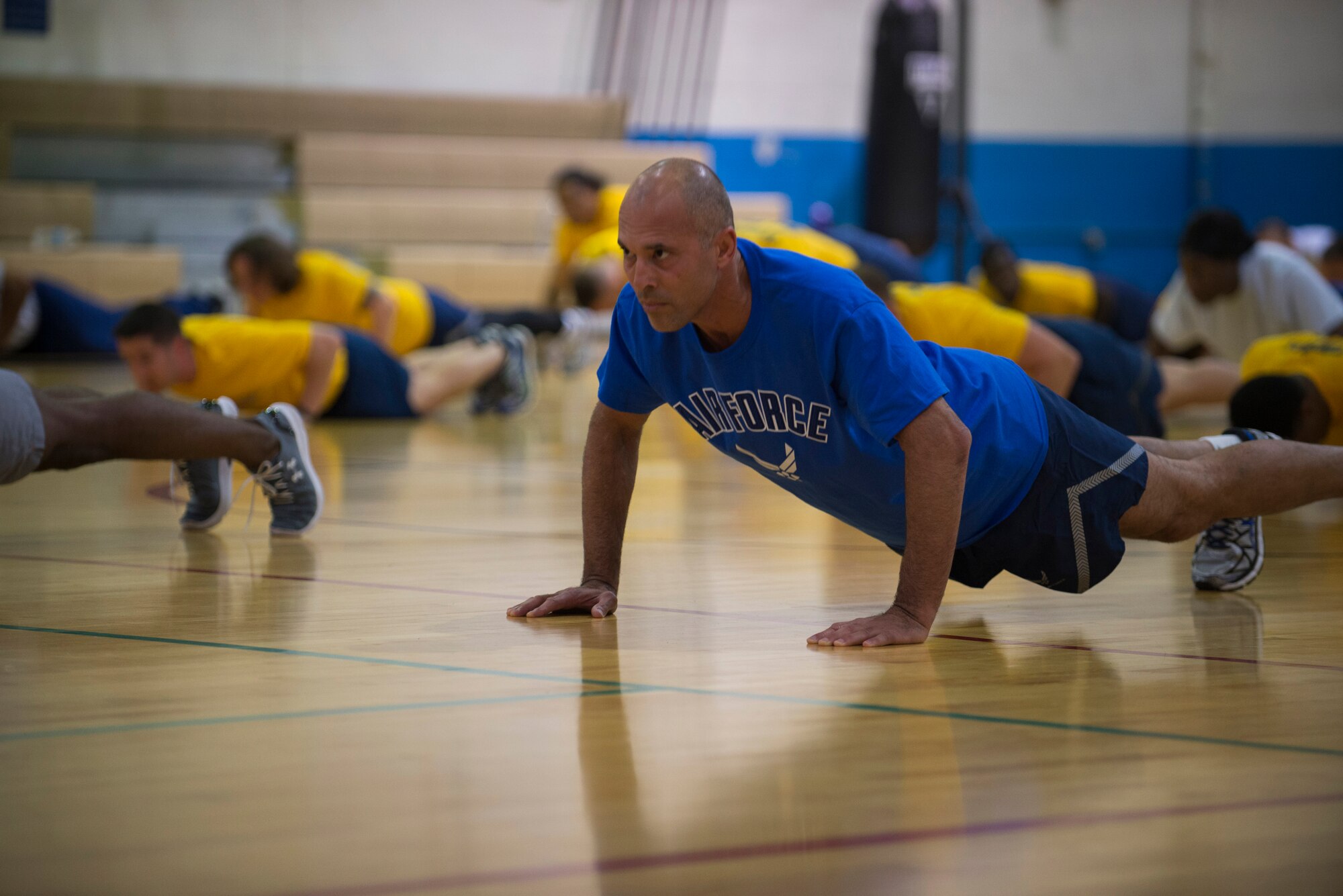 Royce Gracie and Airmen perform pushups during a group work out at the James Gym, Scott Air Force Base, Illinois, June 17, 2015. The fighters taught Airmen fighting techniques after the PTLs warmed them up. (U.S. Air Force Photo by Airman 1st Class Megan Friedl)