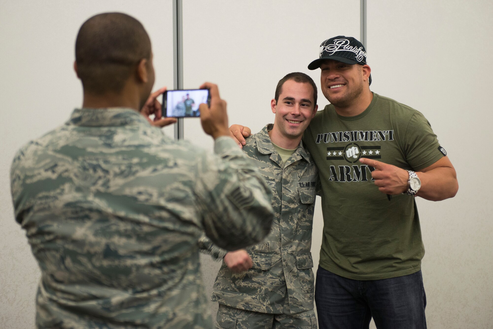 Tito Ortiz and a fan pose for a photo during a meet and great with fans at the Scott Club, Scott Air Force Base, Illinois, June 17, 2015. Ortiz and three other Mixed Martial Arts Bellator fighters visited Scott to meet and sign autographs, take a tour of a C-21 and work out with Airmen. (U.S. Air Force Photo by Airman 1st Class Megan Friedl)