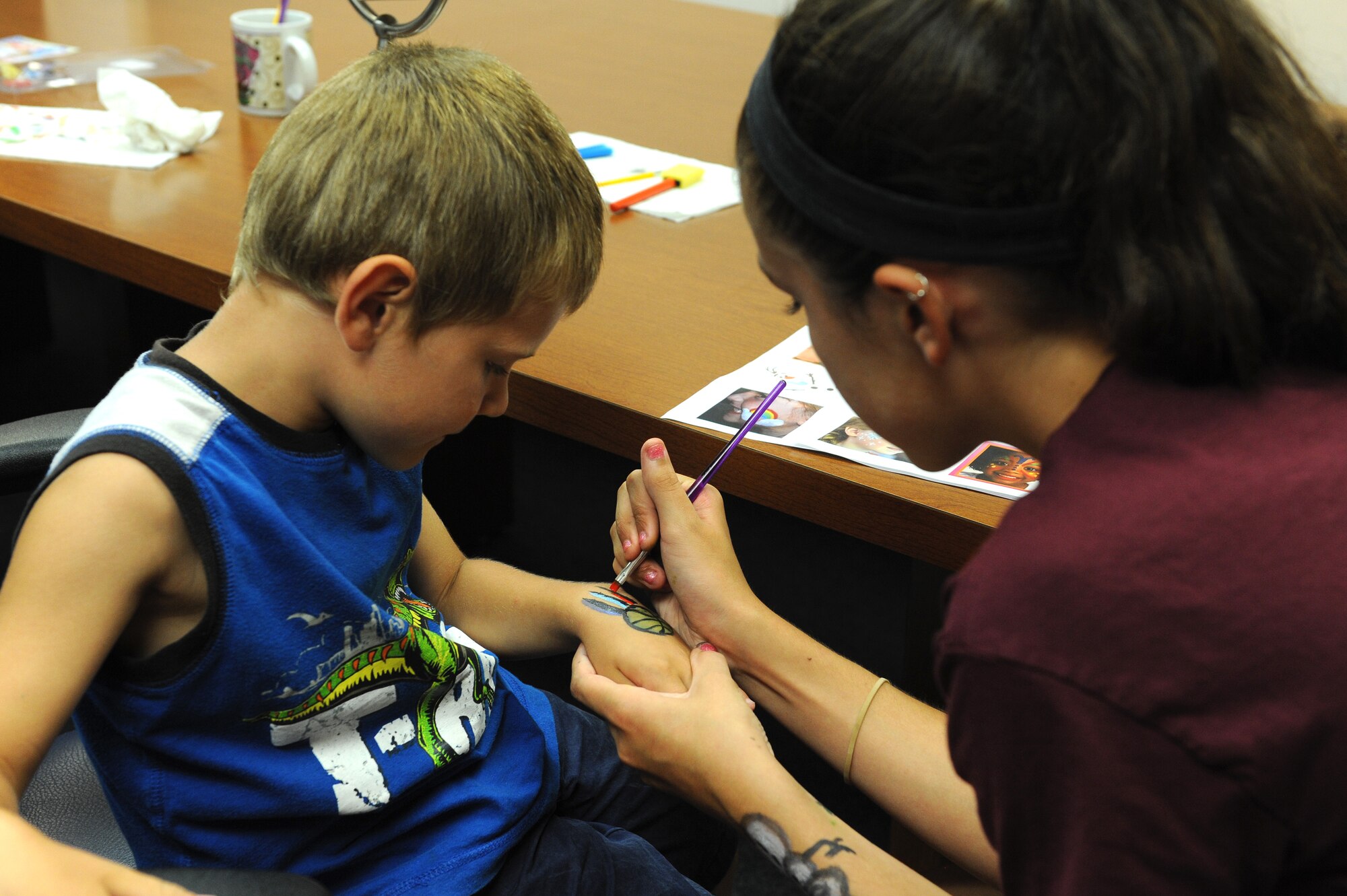 Kaiden Butterfield, 4, gets his hand painted by Alana Driggers, 13, during the Read to the Rhythm Summer Reading Program kick-off event at the library at Scott Air Force Base, Illinois. The purpose of the event was to get children, teens and adults excited about reading throughout the summer. (U.S. Air Force photo by Senior Airman Sarah Hall-Kirchner/Released)