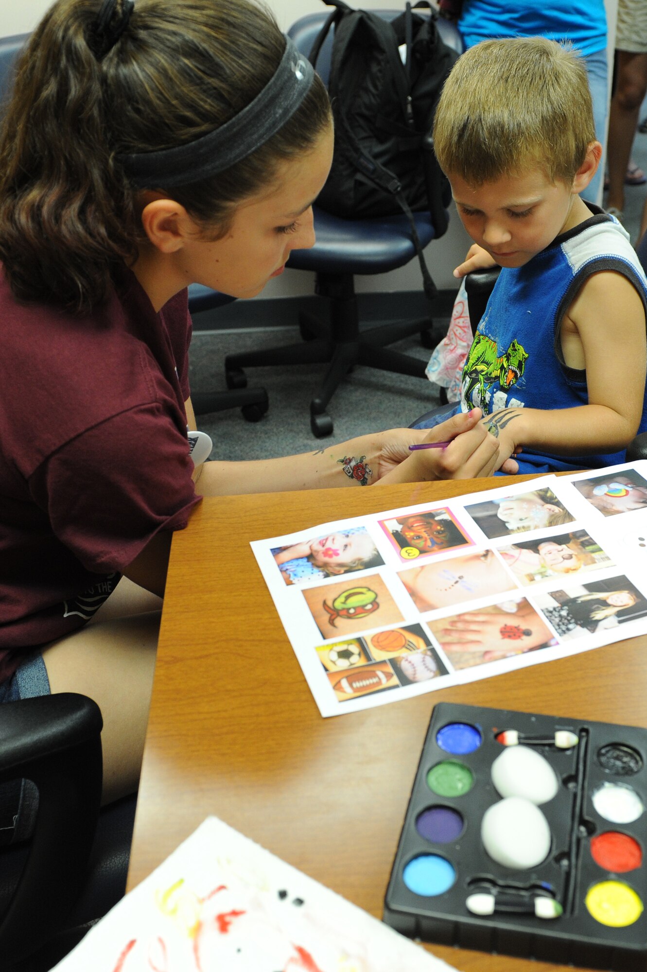Kaiden Butterfield, 4, gets his hand painted by Alana Driggers, 13, during the Read to the Rhythm Summer Reading Program kick-off event at the library at Scott Air Force Base, Illinois. The purpose of the event was to get children, teens and adults excited about reading throughout the summer. (U.S. Air Force photo by Senior Airman Sarah Hall-Kirchner/Released)