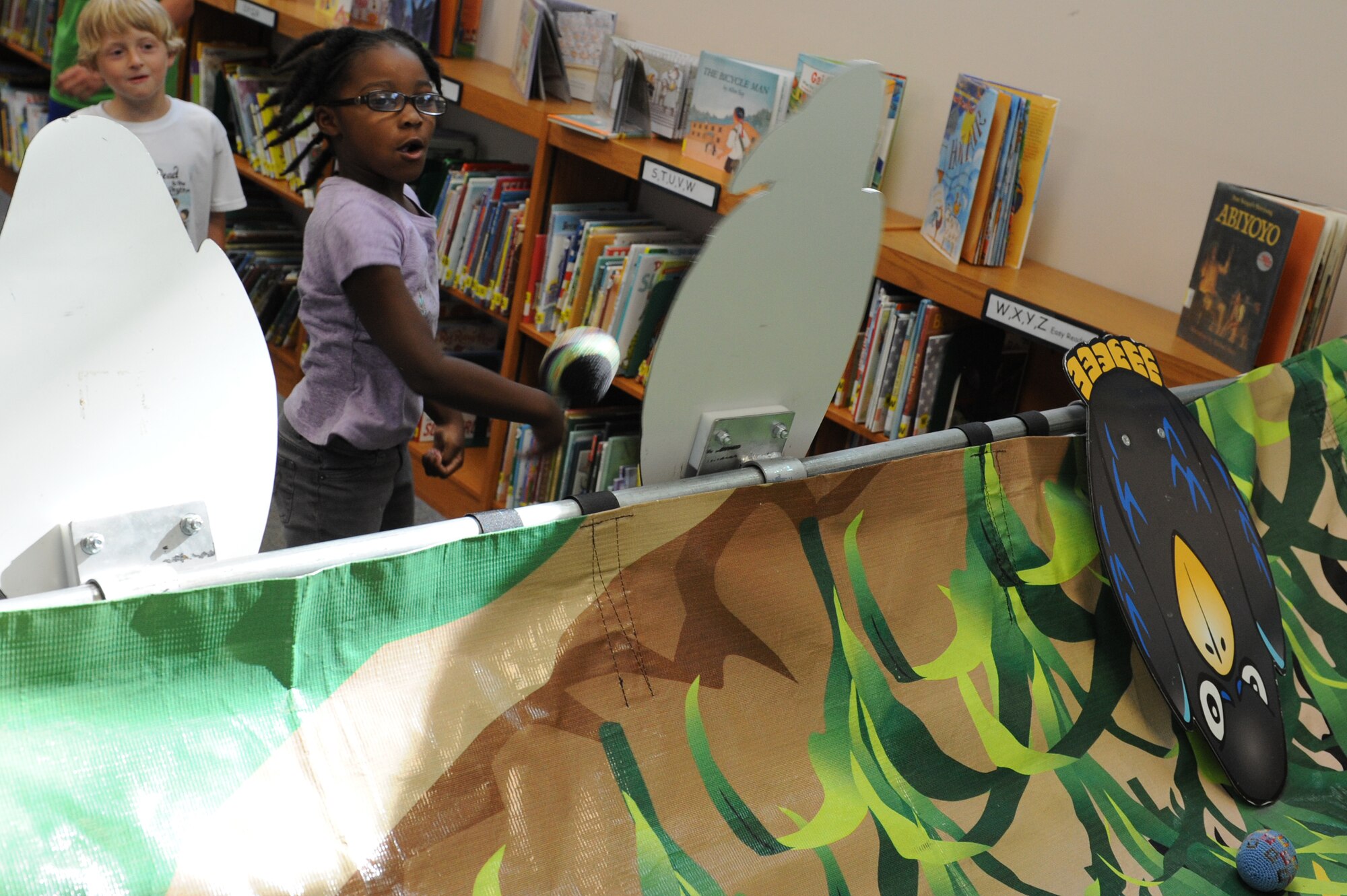 A child throws a ball during a game of knock down during the Read to the Rhythm Summer Reading Program kick-off event at the library at Scott Air Force Base, Illinois. Children and their families were invited to play games, participate in activities, and log reading hours at the event, meant to encourage members of Team Scott to read for leisure. (U.S. Air Force photo by Senior Airman Sarah Hall-Kirchner/Released)