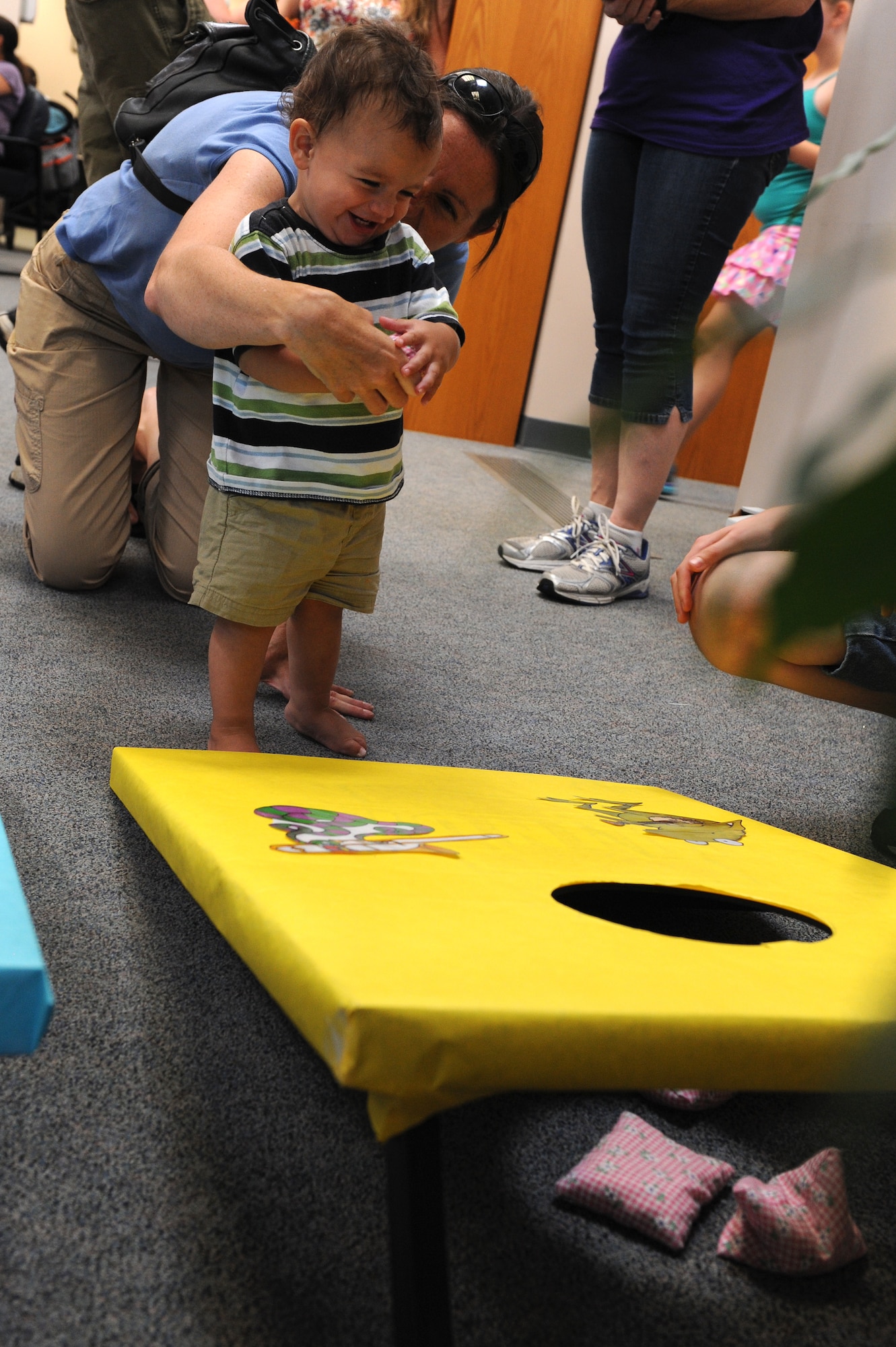 William Ward, 13 months, celebrates success with his mother, Courtney, during the Read to the Rhythm Summer Reading Program kick-off event at the library at Scott Air Force Base, Illinois. The kick-off event included games like corn-hole and knock-down and aimed to get members of Team Scott excited about reading. (U.S. Air Force photo by Senior Airman Sarah Hall-Kirchner/Released)
