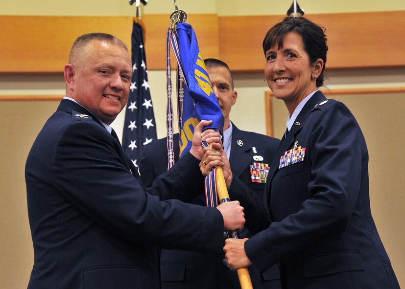 Lt. Col. Courtney Finkbeiner, right, accepts command of the 341st Medical Operations Squadron from Col. Christopher Phillips, 341st Medical Group commander, left, June 23 at the Grizzly Bend. Guidon bearer Master Sgt. Ty Zabel, 341st MDOS superintendent, center, looks on. (U.S. Air Force photo/John Turner)