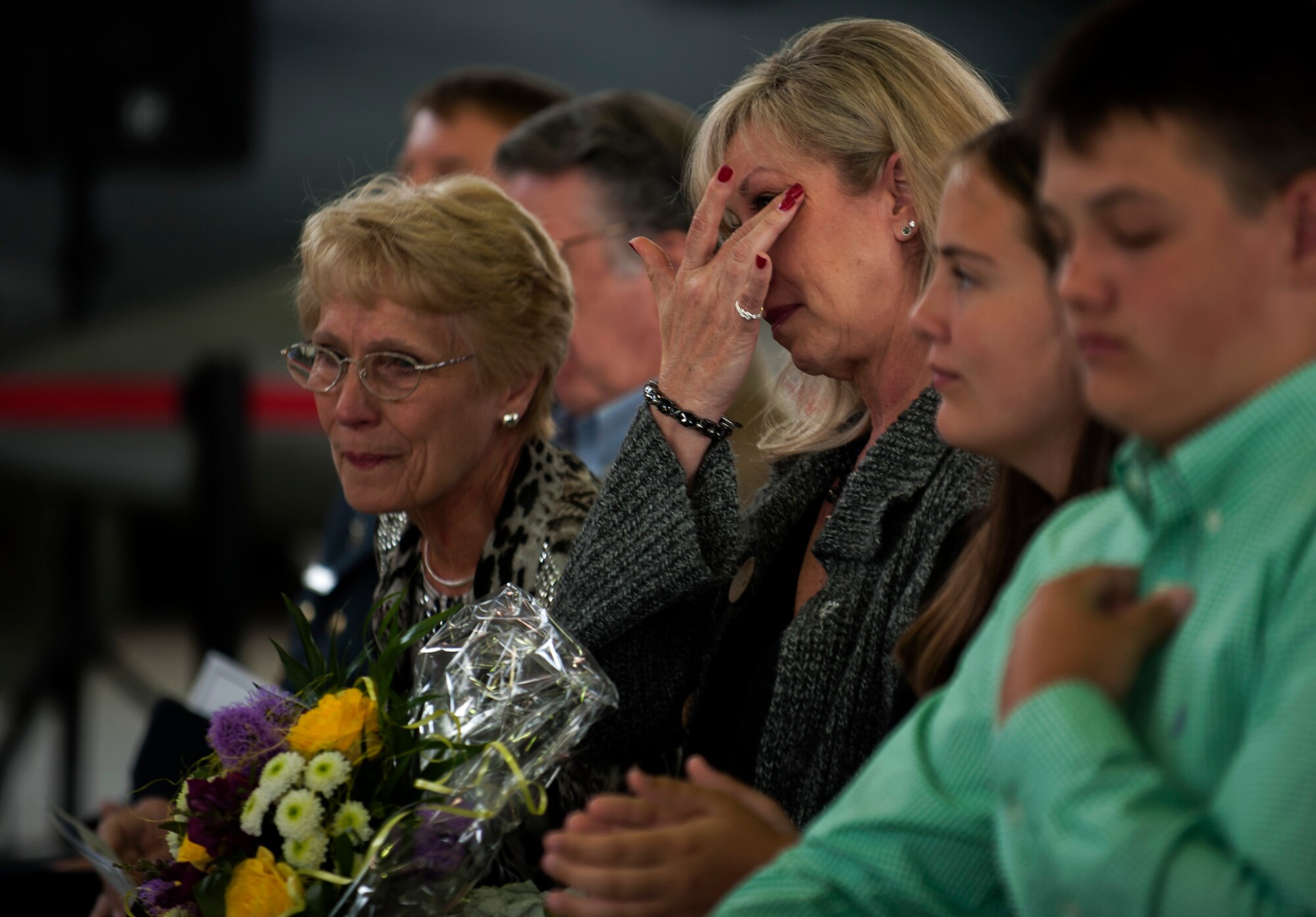 Jaime Humes, spouse of U.S. Air Force Col. James Humes, outgoing 52nd Maintenance Group commander, wipes her eyes during the 52 MXG change of command ceremony in hangar one on Spangdahlem Air Base, Germany, June 18, 2015. Family members of both the outgoing and the incoming commander attended the ceremony and received bouquets as a symbol of gratitude for their support. (U.S. Air Force photo by Airman 1st Class Timothy Kim/Released) 