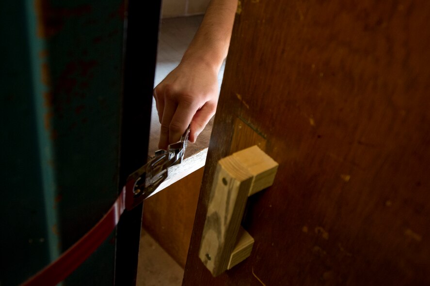 A participant in the 2015 Air Force Research Laboratory Commanders Challenge, deploys a door lock during an active shooter scenario, June, 18, at Muscatatuck Urban Training Center, Butlerville,, Ind., The lock, developed by the team from Wright-Patterson Air Force Base, Ohio, allows for doors without any locks built into them to be locked from the inside, denying entry to any possible threats. (U.S. Air Force photo by Wesley Farnsworth)