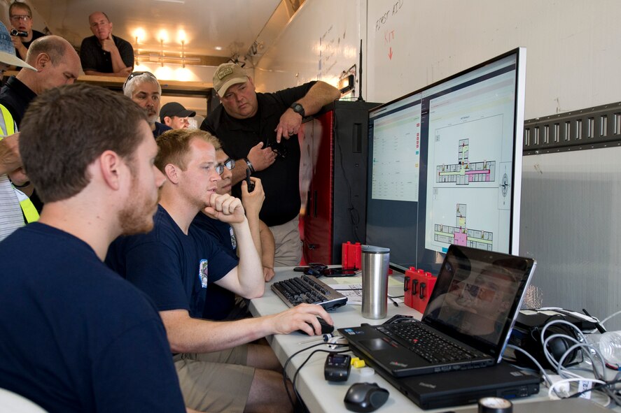 Observers watch as members of the Wright-Patterson Air Force Base, Ohio, 2015 Air Force Research Laboratory Commander Challenge Team, monitor their systems during an active shooter scenario, June 18, at Muscatatuck Urban Training Center, Butlerville,, Ind. Their system allowed for real time tracking of emergency responders allowing dispatchers to direct them where to go in the building using a real time building map showing triggered alarms. (U.S. Air Force photo by Wesley Farnsworth)   