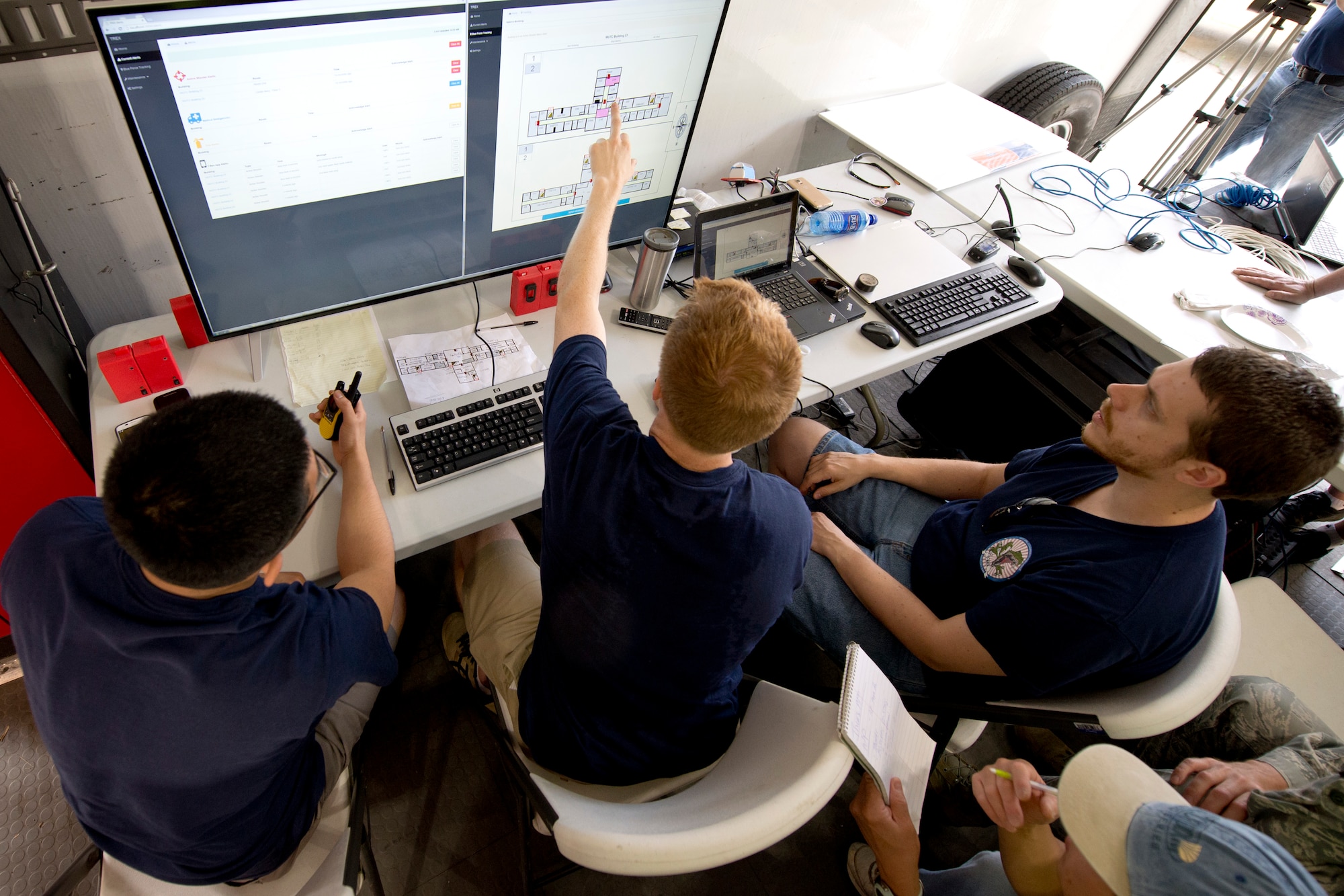 U.S. Air Force 1st Lt. Julian Martinez, Air Force Research Laboratory electrical engineer, Brandon Smith, Air Force Research Laboratory aerospace engineer and Jonathan Boston, AFRL aeronautical engineer, all members of the Wright-Patterson Air Force Base, Ohio, 2015 AFRL Commanders Challenge team monitor their active shooter detection system from their base defense operations center, June 18, at Muscatatuck Urban Training Center, Butlerville,, Ind., Their system allowed for real time tracking of emergency responders allowing dispatchers to direct them where to go in the building using a real time building map showing triggered alarms. (U.S. Air Force photo by Wesley Farnsworth)   