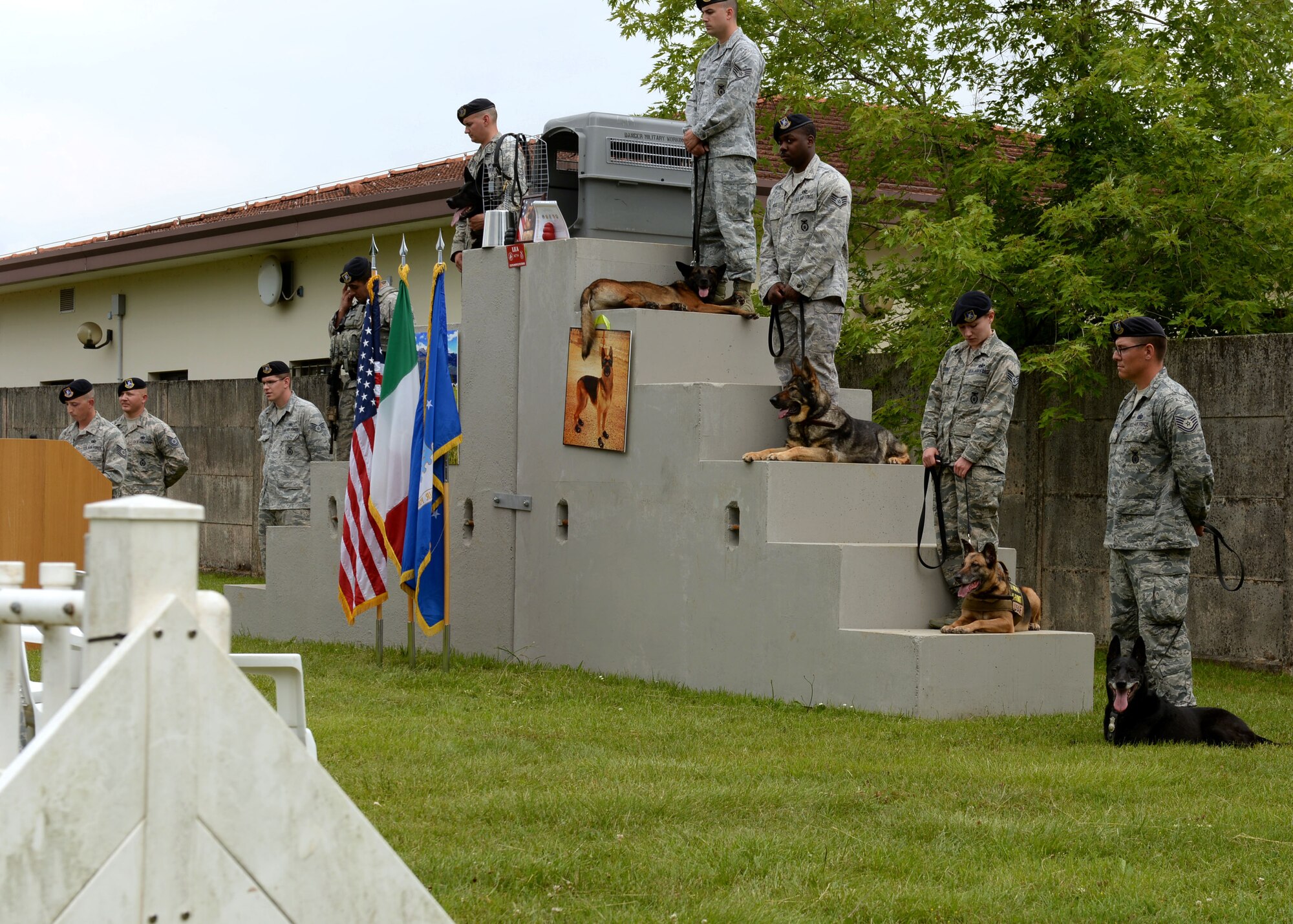 Military working dog handlers from the 31st Security Forces Squadron stand during a MWD memorial and retirement ceremony, June 22, 2015, at Aviano Air Base, Italy. The memorial was held for MWD Lea, who passed away. The handlers stood beside Lea’s crate and personal items while U.S. Air Force Tech. Sgt. Nicholas Ramsey, 31 SFS MWD section NCOIC, gave a speech to the audience. (U.S. Air Force photo by Airman 1st Class Cary Smith/Released)