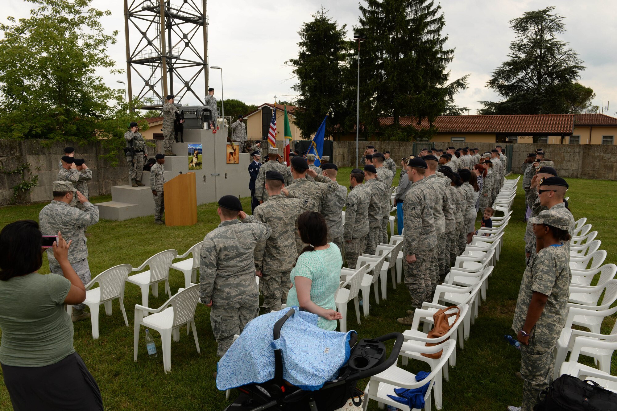 The audience stands during the national anthem at a military working dog memorial and retirement ceremony, June 22, 2015, at Aviano Air Base, Italy. The memorial was held for MWD Lea, who passed away recently. Attendees paused to honor her memory before a poem was read by her handler. (U.S. Air Force photo by Airman 1st Class Cary Smith/Released)