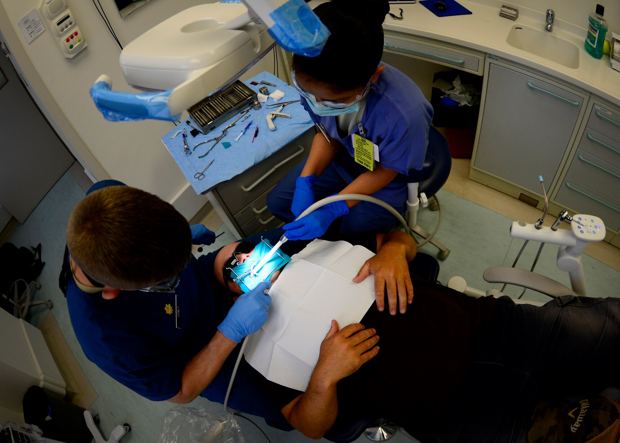 U.S. Air Force Maj. Tann Jones, 31st Dental Squadron dentist, and Airman 1st Class Shannin Mazaredo, 31st Dental Squadron dental assistant fill a cavity for Dustin Drake, 31st Force Support Squadron golf course superintendent, June 23, 2015, at Aviano Air Base, Italy. Dental Airmen ensure the health of the Aviano community by utilizing internal, Department of Defense and host nation resources. (U.S. Air Force photo by Senior Airman Areca T. Wilson/Released)