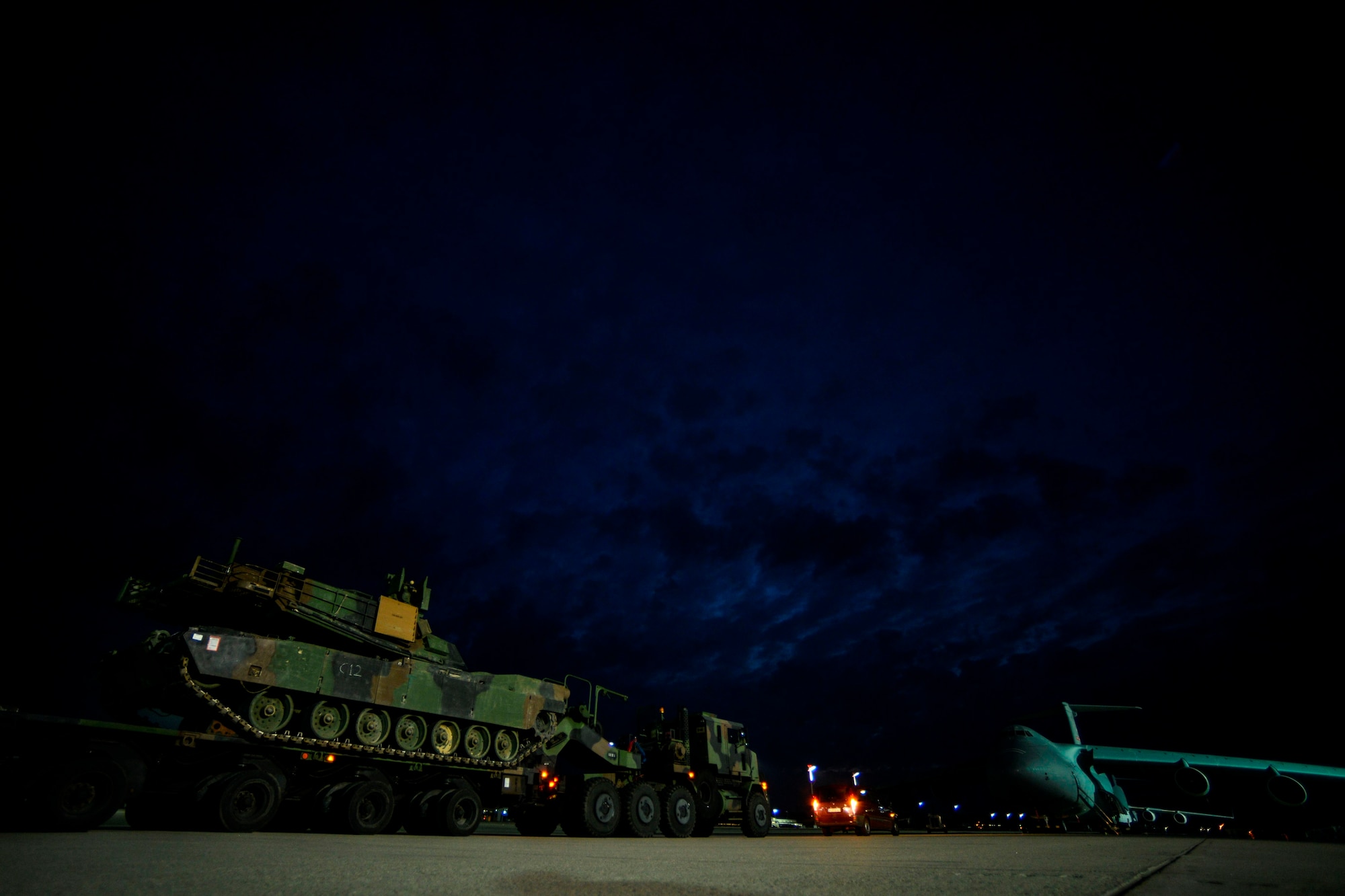 A truck carrying a M1A2 Abrams Main Battle Tank June is parked on the flight line June 20, 2015, Ramstein Air Base, Germany.  The tank was the second to be transported to the Novo Selo Training Area in Bulgaria to participate in  multinational training in support of Operation Atlantic Resolve. (U.S. Air Force photo/Senior Airman Nicole Sikorski)