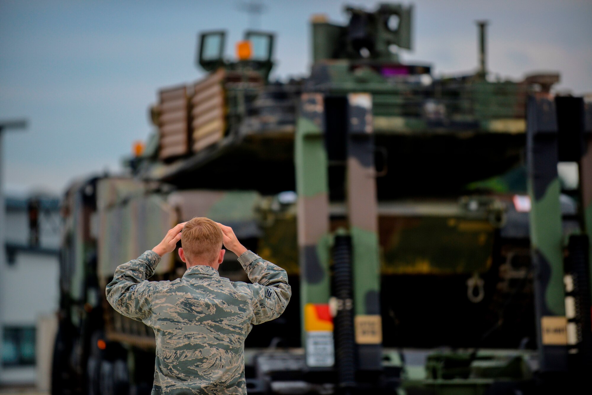 Senior Airman Matthew Boheler, 721st Aerial Port Squadron air transportation specialist, directs a truck carrying an M1A2 Abrams main battle tank June 20, 2015, Ramstein Air Base, Germany.  Airmen and Soldiers worked together to transport two tanks to Bulgaria to aid the U.S. Army Europe led training in support of Operation Atlantic Resolve. (U.S. Air Force photo/Senior Airman Nicole Sikorski)