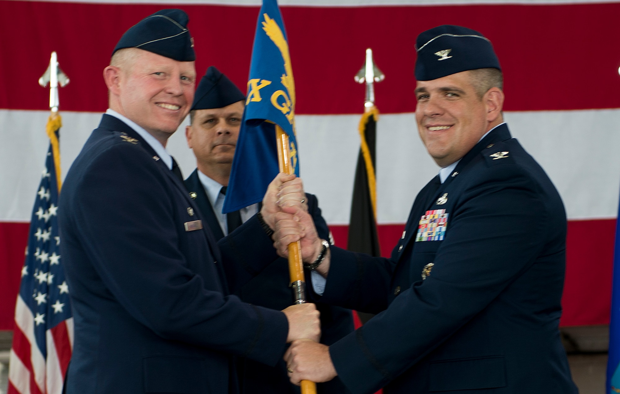 U.S. Air Force Col. Joe McFall, 52nd Fighter Wing commander, left, passes the ceremonial guidon to U.S. Air Force Col. Stephen Scherzer, incoming 52nd Maintenance Group commander, right, during the 52 MXG change of command ceremony in Hangar 1 on Spangdahlem Air Base, Germany, June 18, 2015. Scherzer served as Deputy Commander of the 83rd Training Group at Sheppard Air Force Base, Texas before arriving to Spangdahlem. (U.S. Air Force photo by Airman 1st Class Timothy Kim/Released)