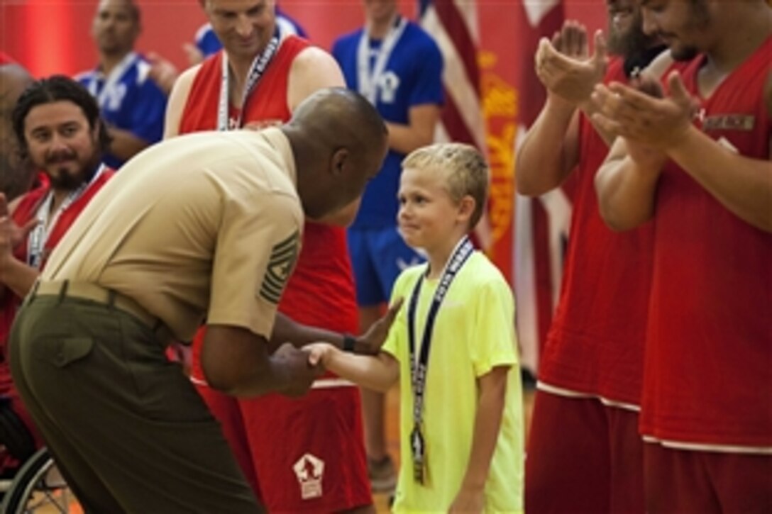 U.S. Marine Corps veteran Clayton McDaniels’ son receives a gold medal on behalf of his father whose team won the wheelchair basketball championship game at the 2015 Department of Defense Warrior Games on Marine Corps Base Quantico, Va., June 23, 2015.