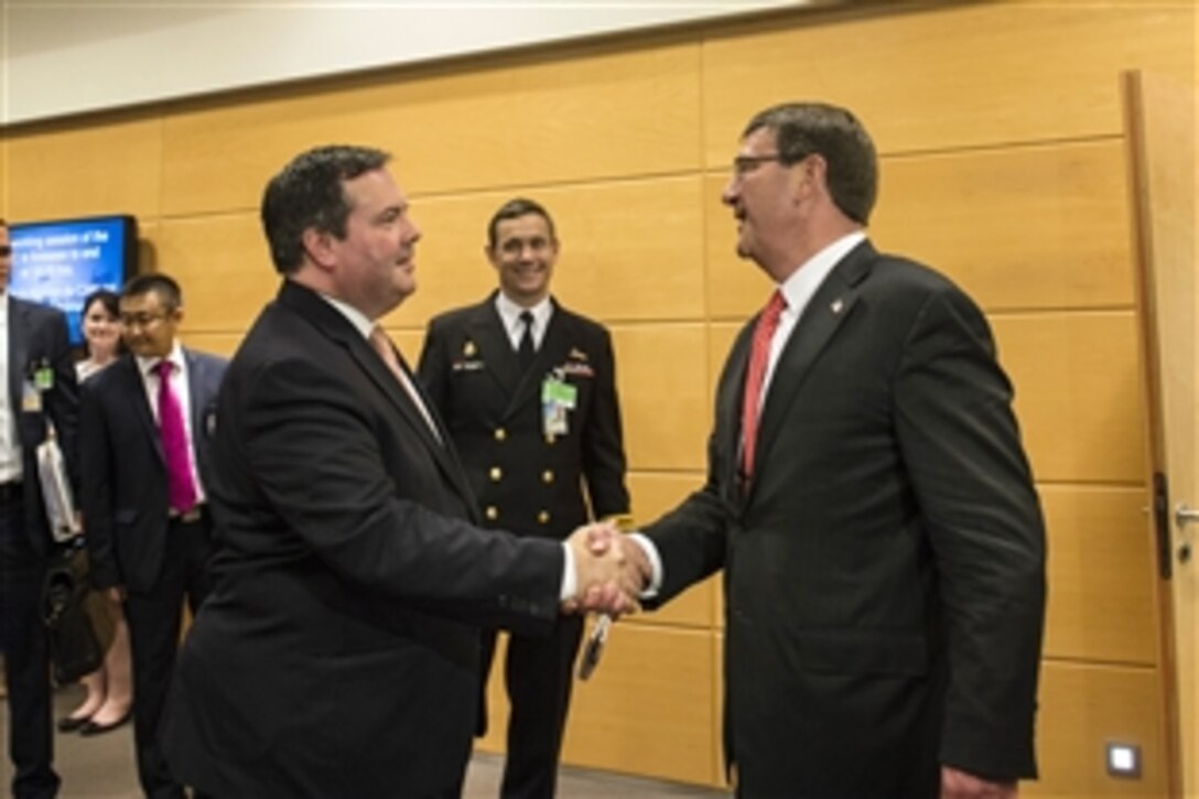 U.S. Defense Secretary Ash Carter, right, greets Canadian Defense Minister Jason Kenney at NATO headquarters in Brussels, June 24, 2015, before meeting to discuss matters of mutual importance.