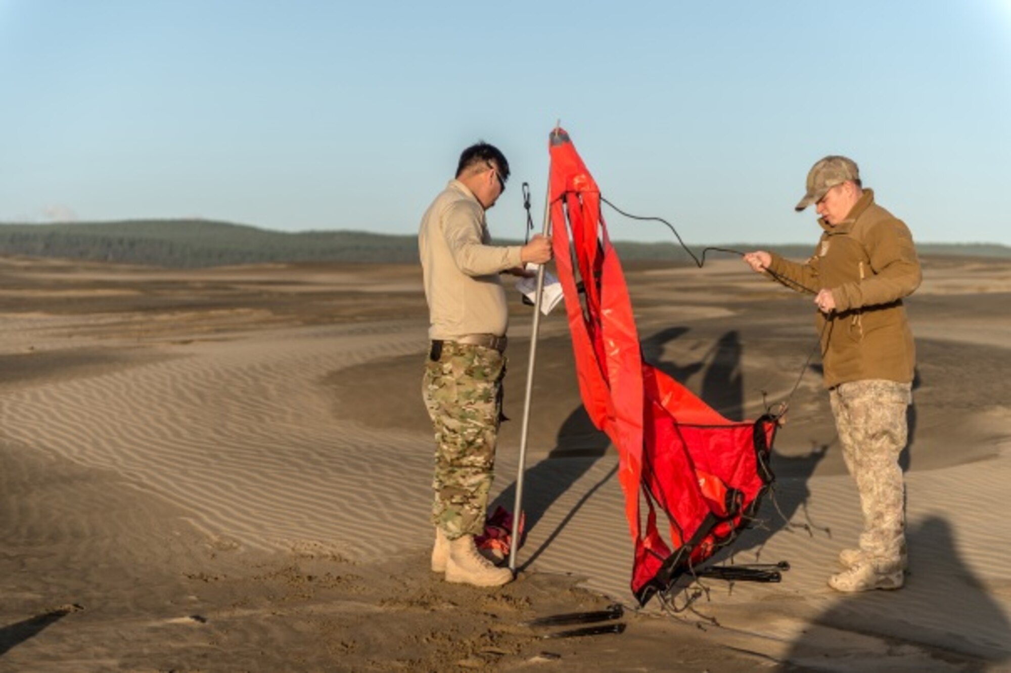 U.S. Air Force Master Sgt. Matthew Packer (left) from the 353rd Special Operations Support Squadron and New Zealand Army Staff Sergeant Peter Baker (right) prepare a marker at a Drop Zone (DZ) in Kaipara, New Zealand, June 22, 2015 prior to air drops conducted by a 1st Special Operations Squadron MC-130H Combat Talon II aircraft.  Members from the 353rd Special Operations Group and the Royal New Zealand Air Force and Army are participating in Exercise Flash Lantern Net June 18-27 at Royal New Zealand Air Force Base Auckland in New Zealand.  (New Zealand Defense Force photo by Roderick Mackenzie)

