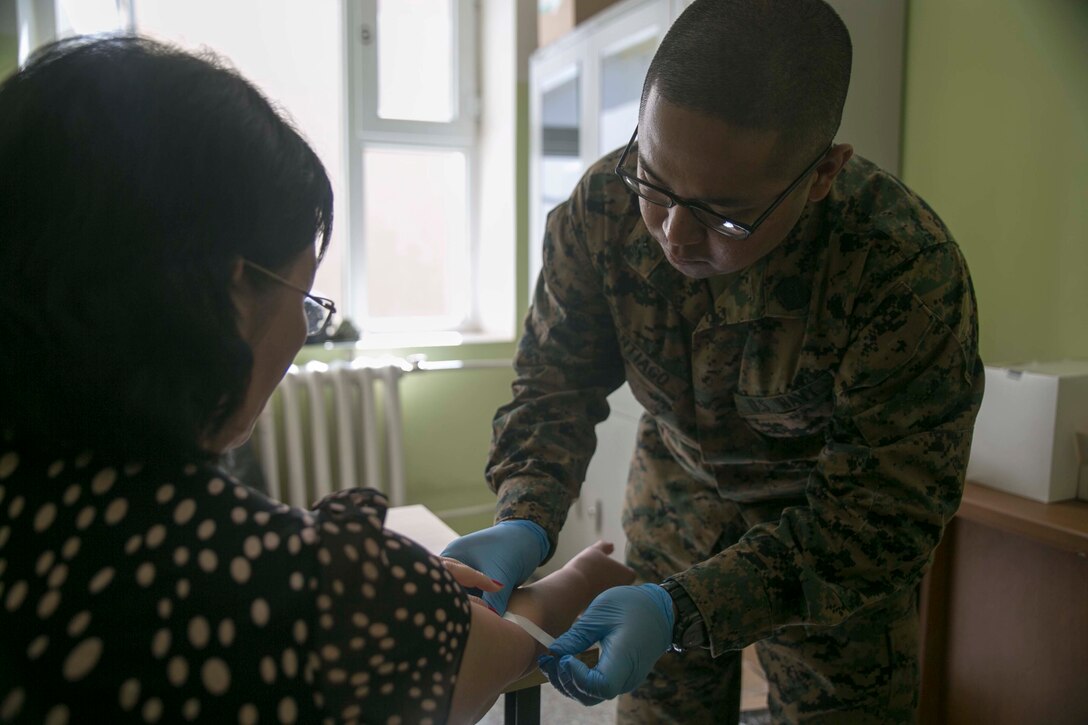 U.S. Navy Petty Officer 2nd Class Leonard A. Santiago, right, from Olongapo City, Philippines, provides medical care to a Mongolian resident as part of the health services support engagement during Khaan Quest 2015 at the 79th High School in Ulaanbaatar, Mongolia, June 21. Khaan Quest is a regularly scheduled, multinational exercise hosted annually by the Mongolian Armed Forces and co-sponsored by U.S. Army, Pacific, and U.S. Marine Corps Forces, Pacific. Santiago is a hospital corpsman with 3rd Medical Battalion, 3rd Marine Logistics Group, III Marine Expeditionary Force. 