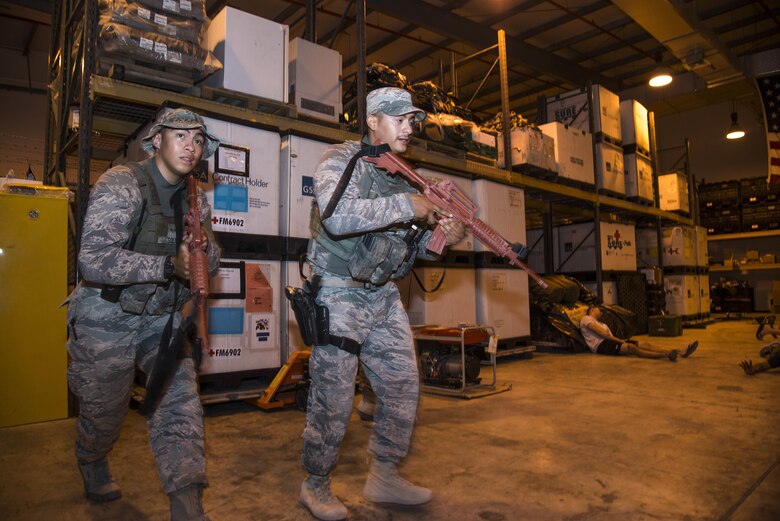 U.S. Air Force Senior Airmen Julian Solis and Morgan Esquerra search a medical warehouse for an active shooter after responding to a simulated 911 call during a battle drill June 19, 2015, at Al Udeid Air Base, Qatar. Several agencies of the 379th Air Expeditionary Wing were tested on their reaction to a possible active shooter scenario if an on-base incident truly ever occurred. (U.S. Air Force photo by Tech. Sgt. Rasheen Douglas)