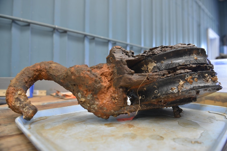 Nautical tackle from the CSS Georgia. Tackle was used to move objects topside on the ship. A closer look reveals tracks left by teredo worms, which are organisms that consume wood in watery environments. Damage from teredo worms can be seen on the right side of the artifact.