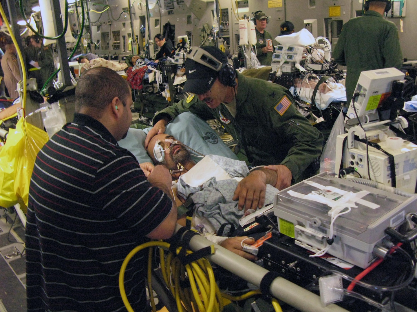 Air Force Col. (Dr.) Charles Chappuis, a surgeon on a three-member Air National Guard critical-care air transport team, talks with Spc. Adam Castagna, one of three critical patients under his care during a C-17 Globemaster III flight from Ramstein Air Base, Germany, to Joint Base Andrews, Md., as Castagna's brother, Mike Castagna, looks on, April 29, 2011.