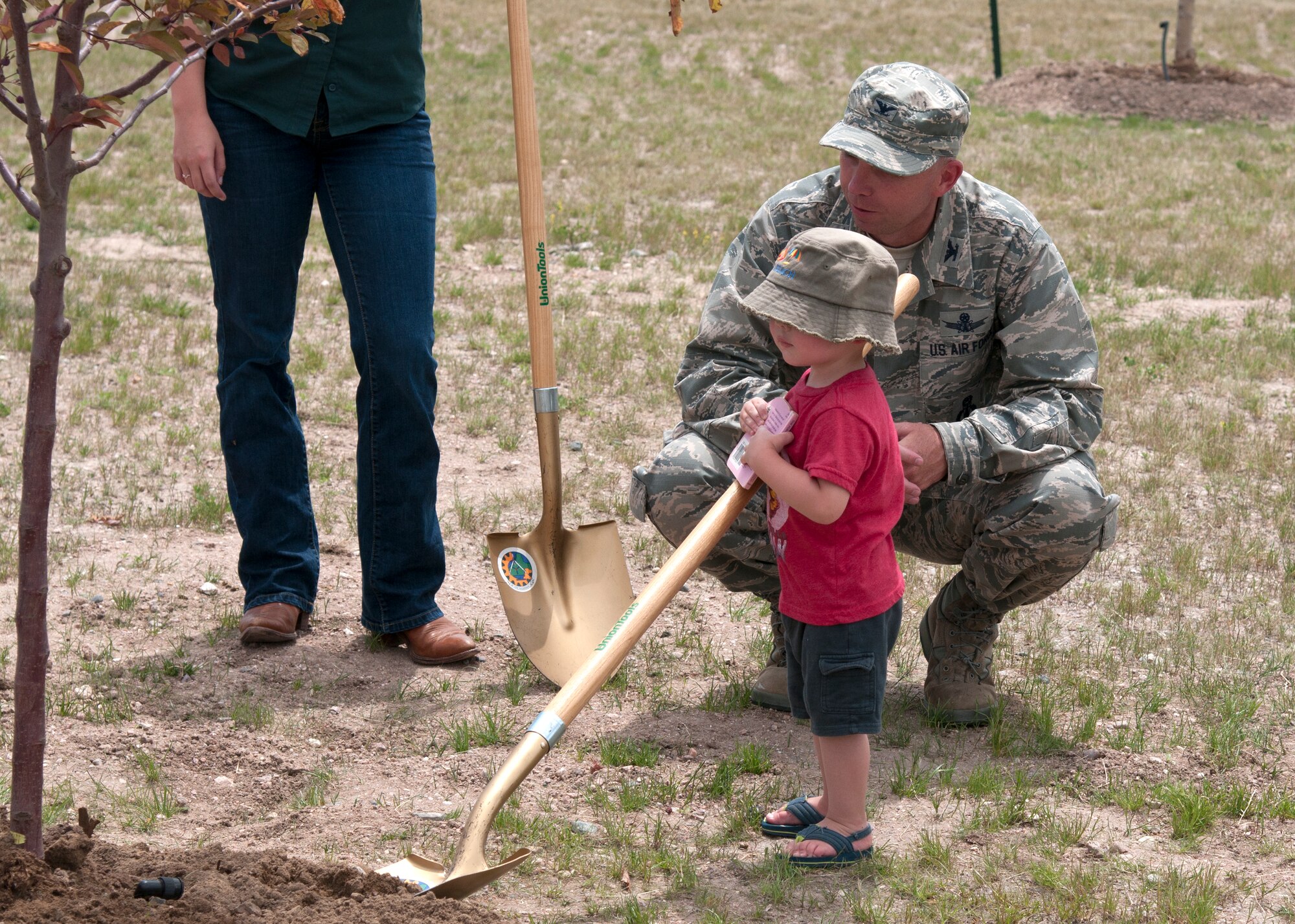 Col. Ronald Allen, 90th Missile Wing vice commander, and Aceson Heuck, 1, son of Senior Airmen Anthony Heuck, 90th Maintenance Operations Squadron vehicle and equipment section technician, look at the tree planted on F.E. Warren Air Force Base, Wyo., June 24, 2015. This tree planting event marks F.E. Warren’s 27th consecutive year of participation in the Tree City USA program. (U.S. Air Force photo by Airmen 1st Class Malcolm Mayfield)