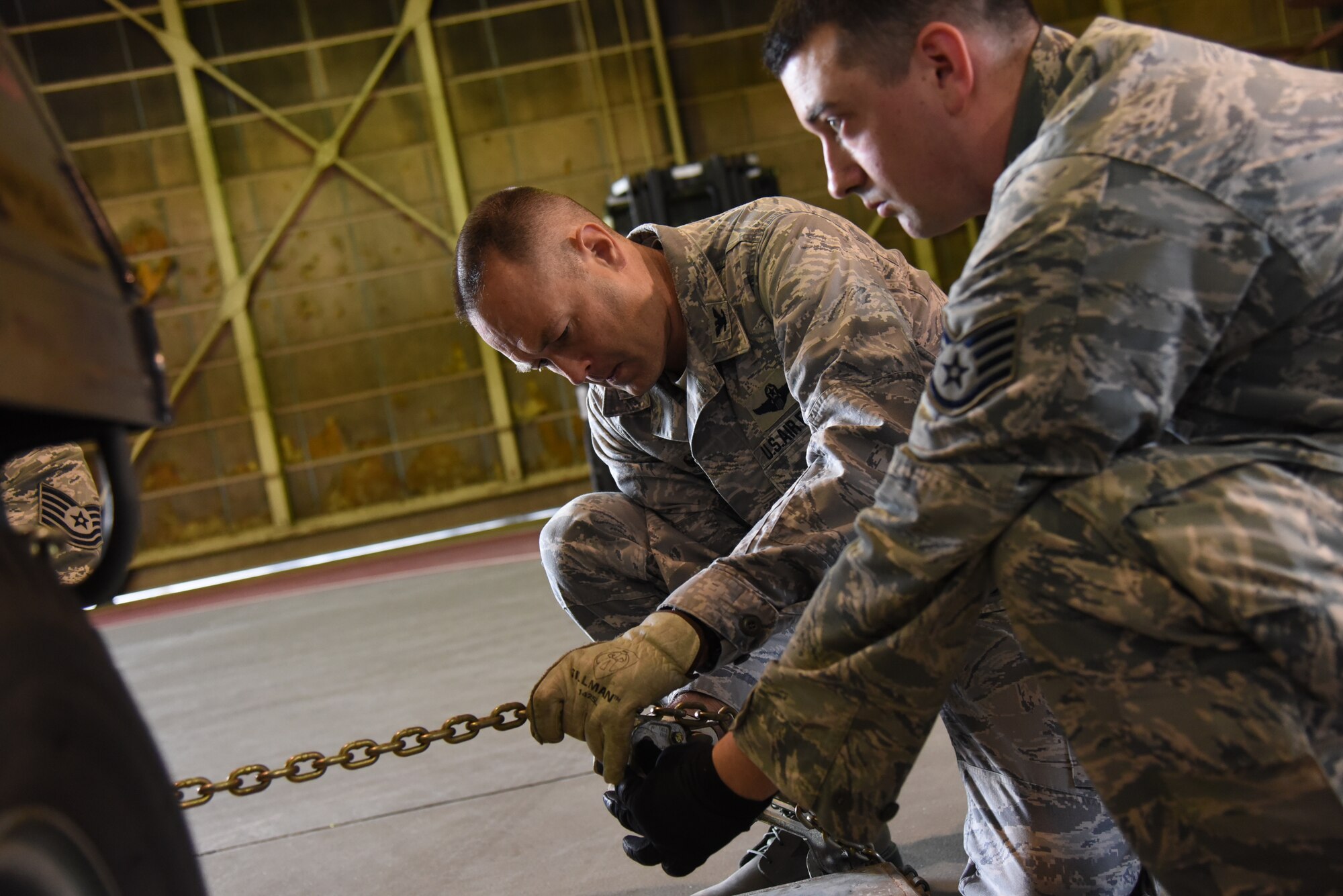 U.S. Air Force Col. Timothy Sundvall, 35th Fighter Wing commander, and Staff Sgt. Christopher Bryant, 35th Logistic Readiness Squadron outbound cargo supervisor, secure a chain to a pallet at Misawa Air Base, Japan, June 22, 2015. After loading an object onto a pallet, Sundvall and Bryant then secured it with chains to ensure it would be stable enough for flight. (U.S. Air Force photo by Senior Airman Patrick S. Ciccarone/Released)