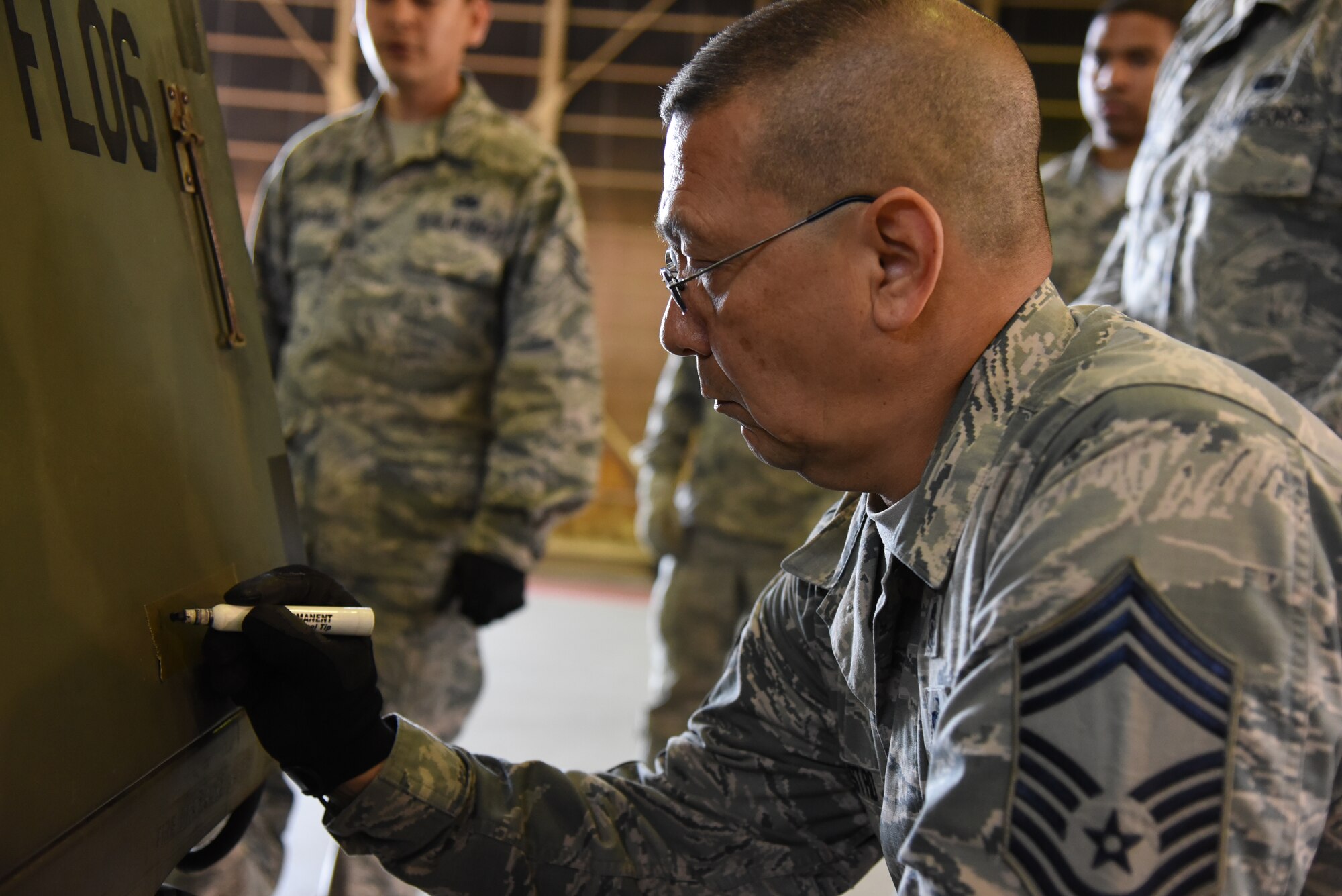 U.S. Air Force Chief Master Sgt. Leonardo Castro, 35th Fighter Wing interim command chief, writes down the exact weight of a palletized object at Misawa Air Base, Japan, June 22, 2015. After calculating where the center of gravity for the object is, Castro wrote the number down, along with instructions for how the object should be handled. (U.S. Air Force photo by Senior Airman Patrick S. Ciccarone/Released)