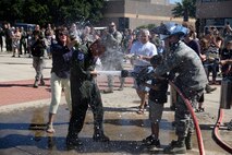 Col. Brian Hastings, commander of the 47th Flying Training Wing, receives his salutatory shower after his final flight here at Laughlin Air Force Base, Texas, June 25, 2015. Military aviators have a tradition where aircrew members upon completion of their final flight, or "fini flight" are met and hosed down with water by their fellow comrades, family, and friends. (U.S. Air Force photo by Airman 1st Class Brandon May) 